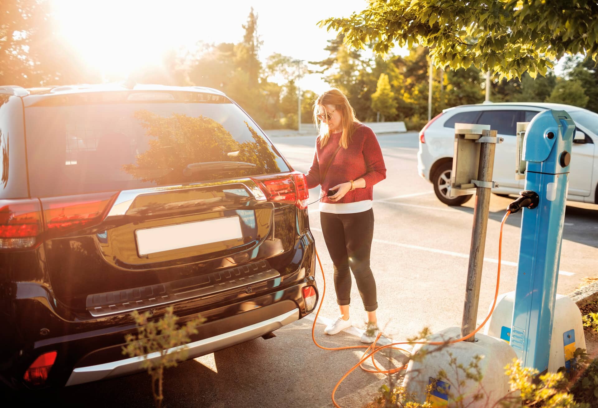 Chica recargando un coche eléctrico.