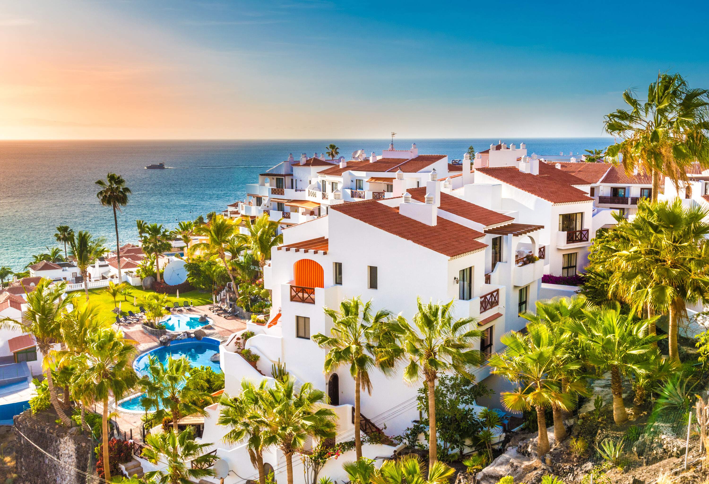 A resort town with palm trees and whitewashed houses overlooking the endless sea.