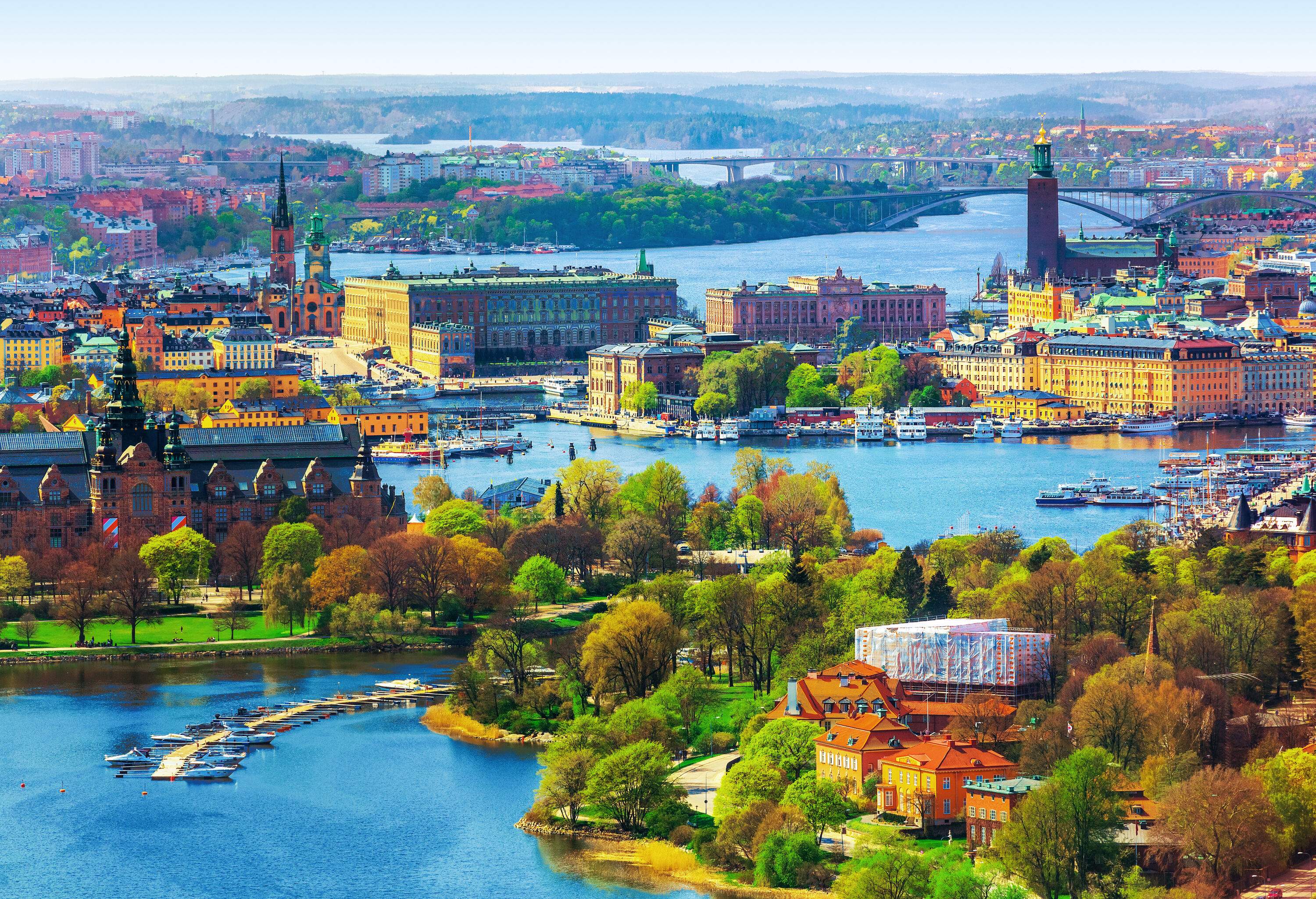 A city split in two by a body of water, with lots of green trees and several ports.