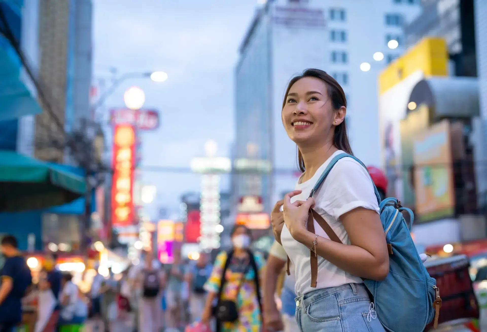 Young asian woman traveler with a backpack on her shoulder and travel hat walking on footpath over China town, Bangkok, Thailand