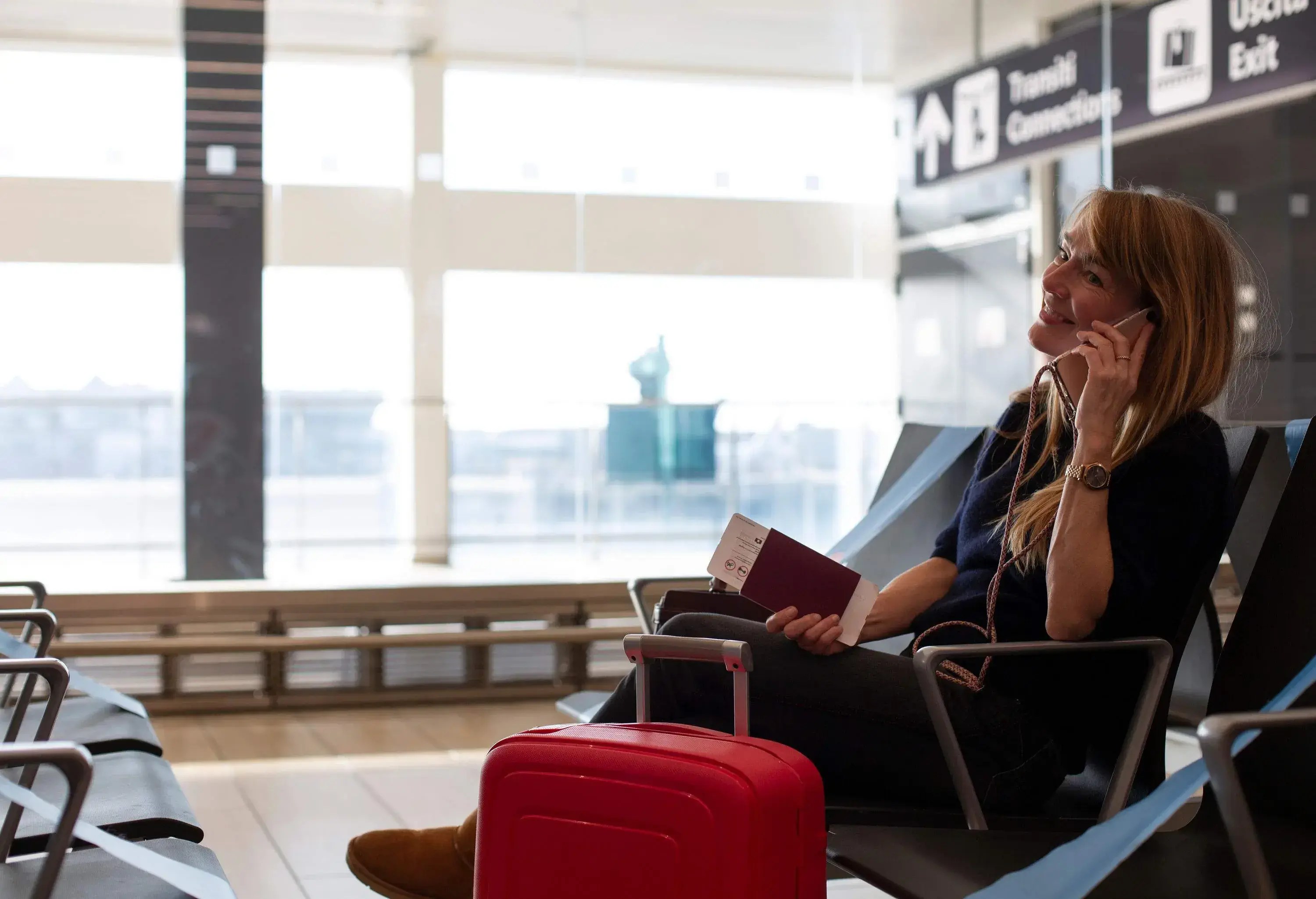 A women waiting at an airport and talking on the phone.