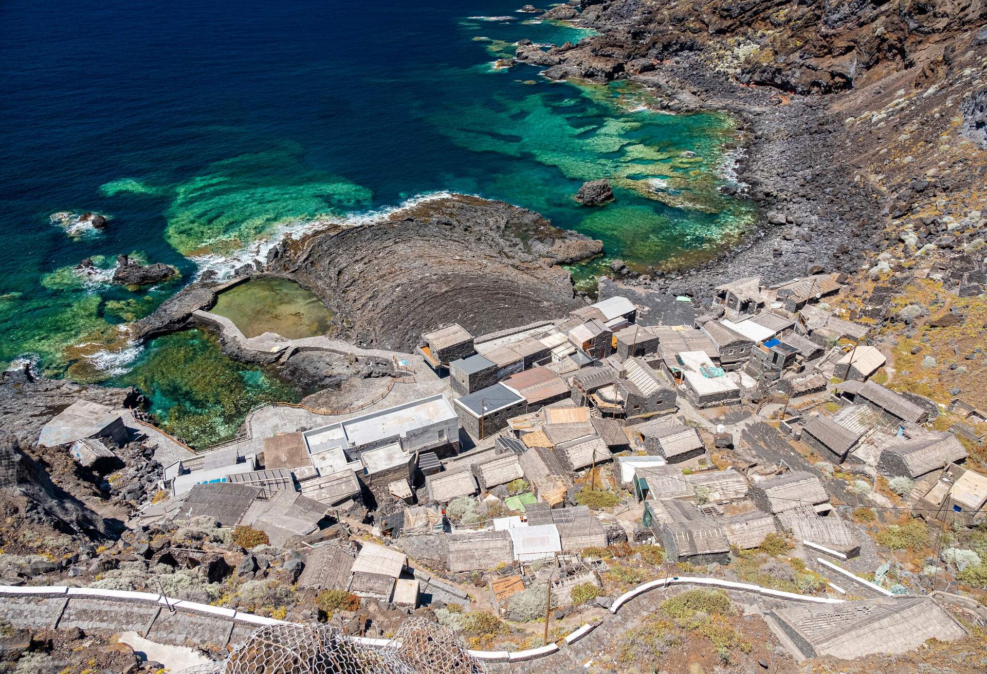 Stock photo of a volcanic coastline with turquoise blue water in an abandoned village. Aerial view of El Pozo de las Calcosas, El Hierro, Canary Island.