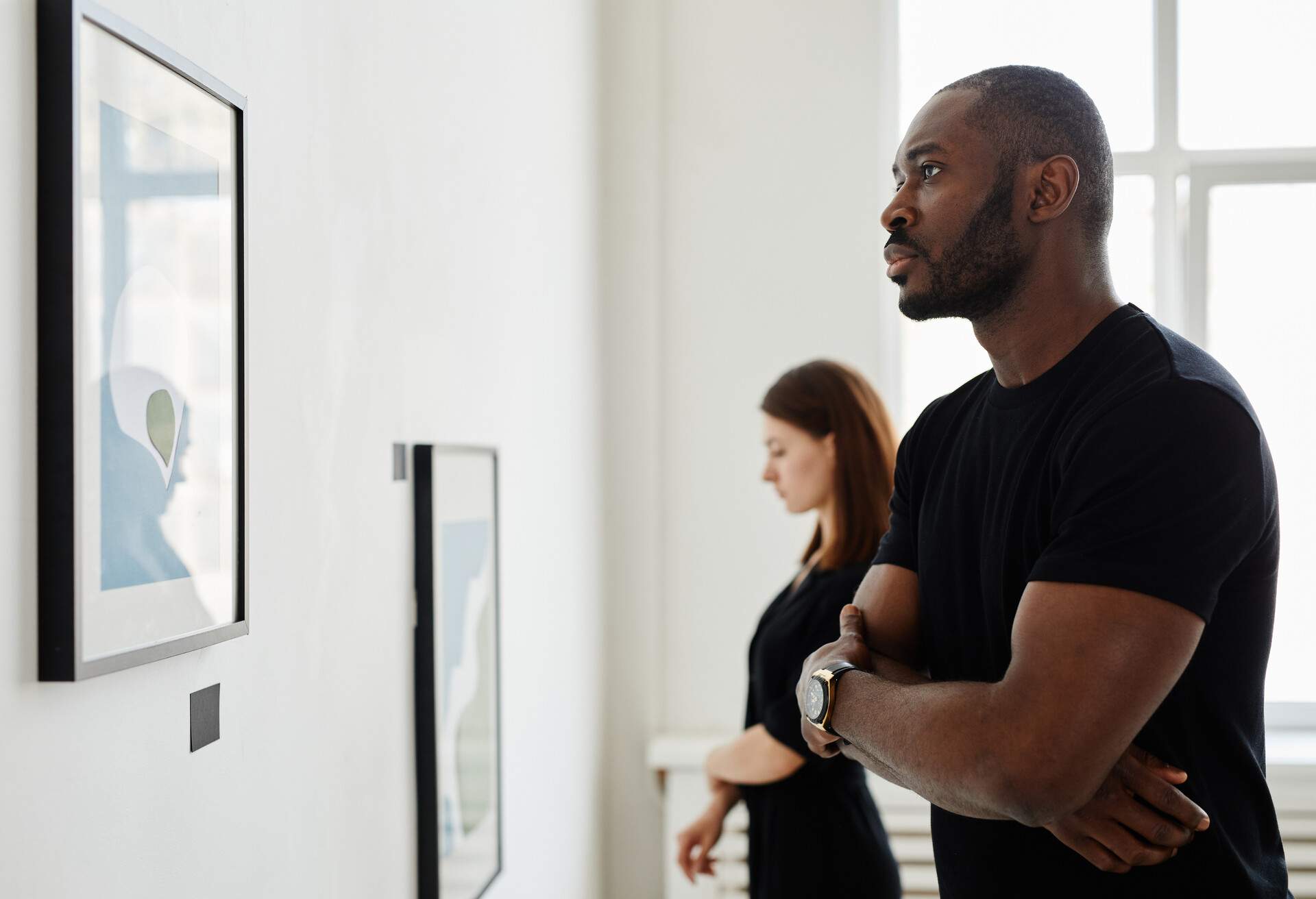 Minimal side view portrait of African-American man looking at paintings in modern art gallery, copy space