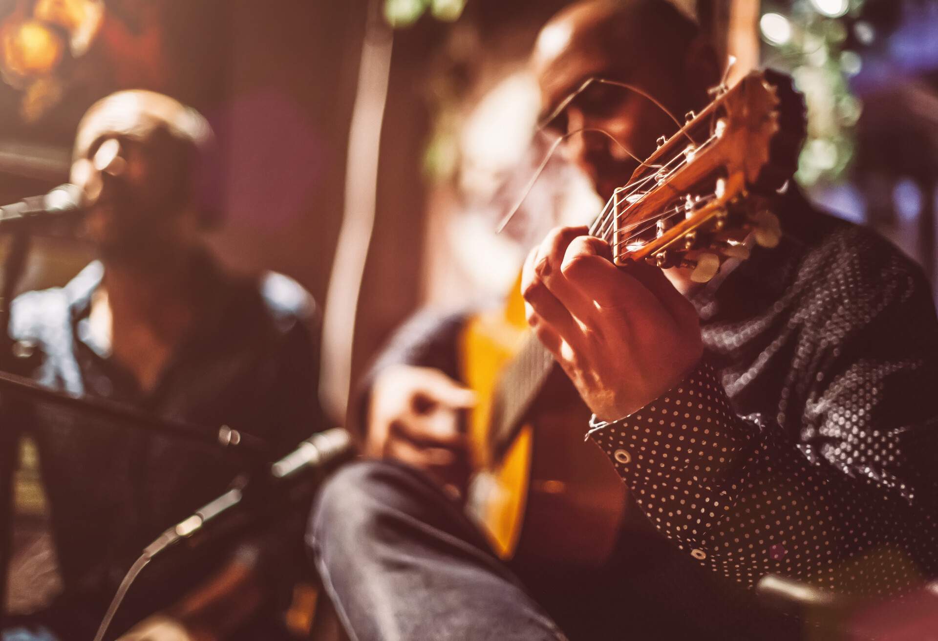 Two male musicians on a stage performing traditional flamenco music.