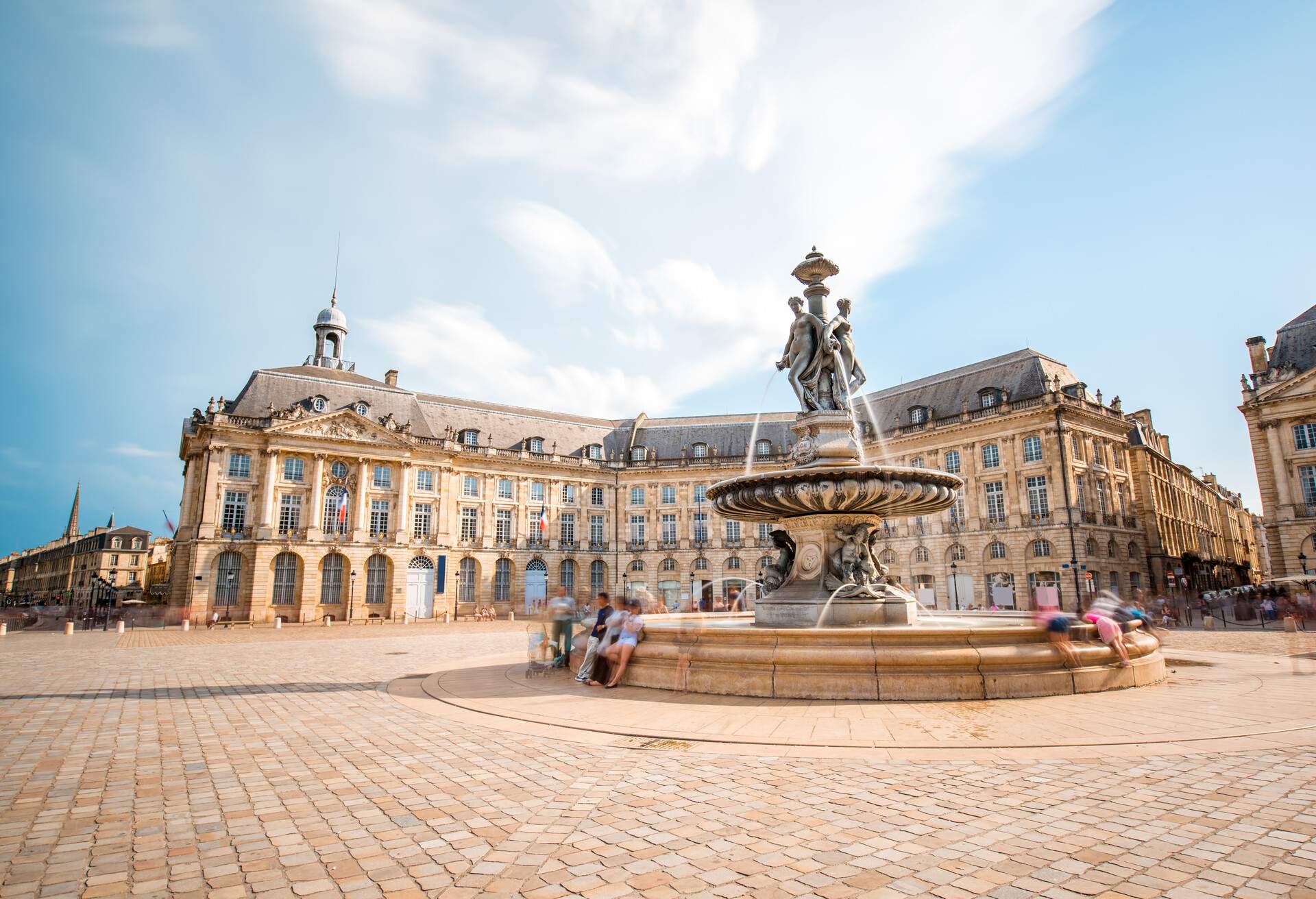 View on the famous La Bourse square with fountain in Bordeaux city, France. Long exposure image technic with motion blurred people and clouds