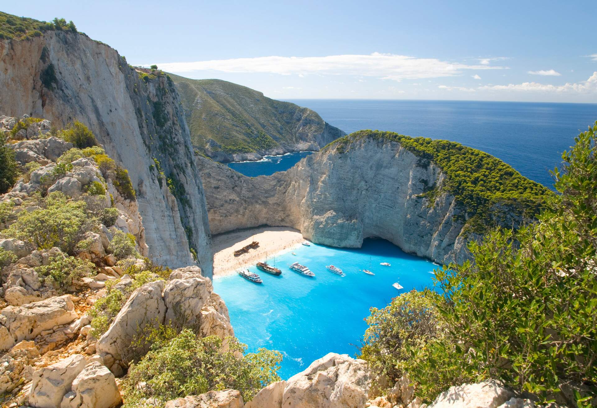 View from clifftop over the turquoise waters of Navagio Bay (aka Shipwreck Bay, Smugglers Cove), pleasure boats anchored off the beach, near Anafonitria, Zakynthos (aka Zante, Zakinthos), Ionian Islands, Greece, Europe.