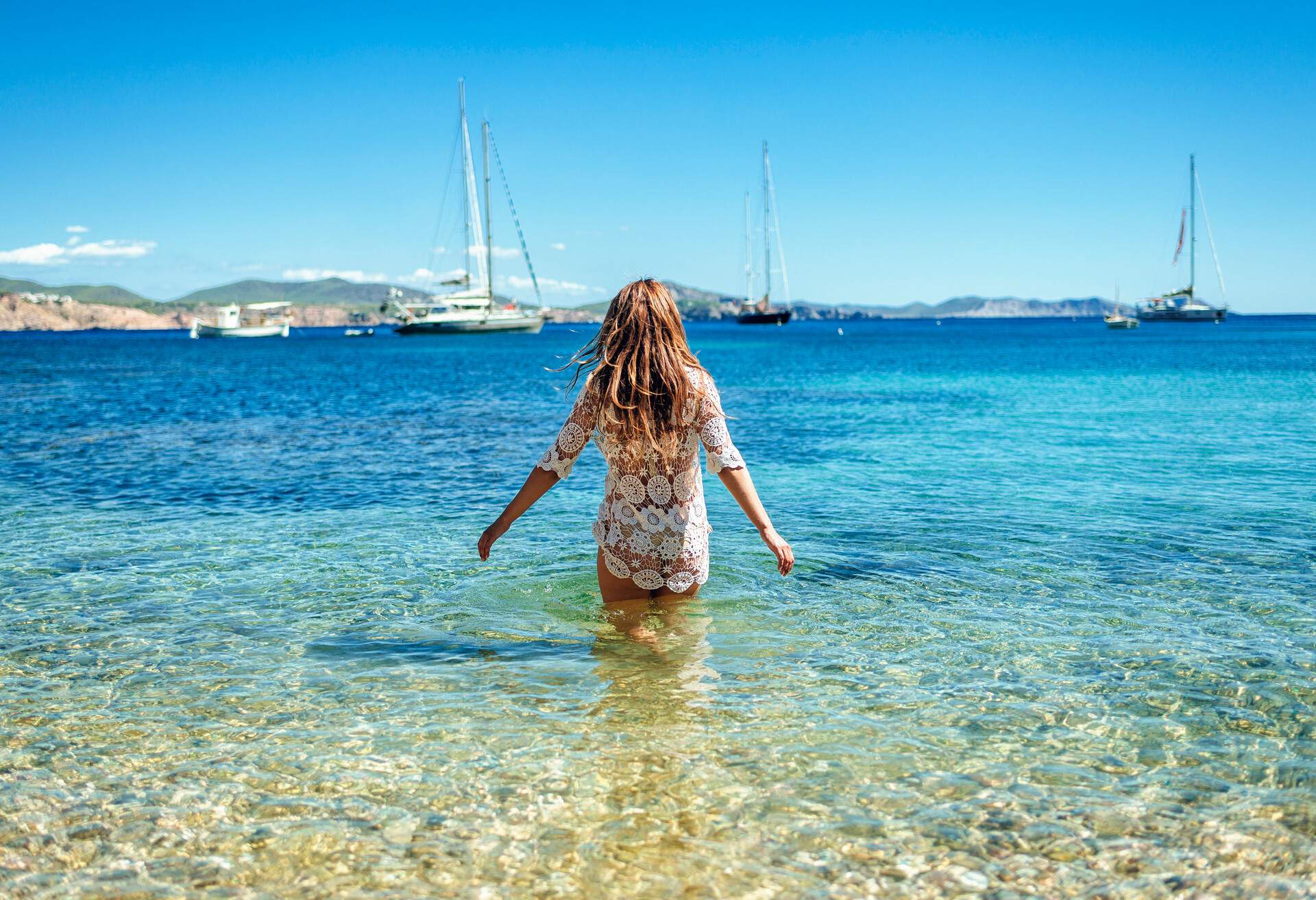 Woman from behind in the water at Llentrisca Beach in Ibiza, Balearic Islands, Spain.