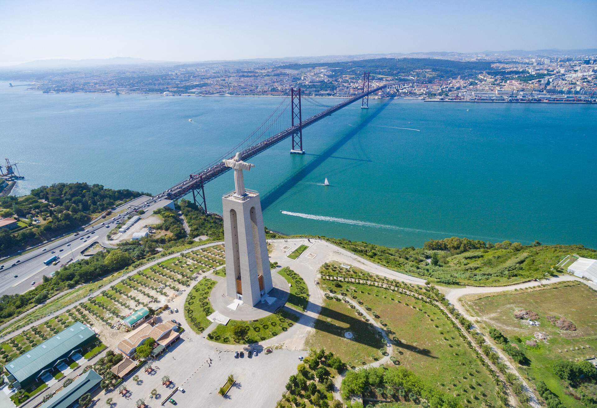 Aerial view of Sanctuary of Christ the King overlooking Lisbon and 25 de Abril Bridge connecting Lisbon and Almada.