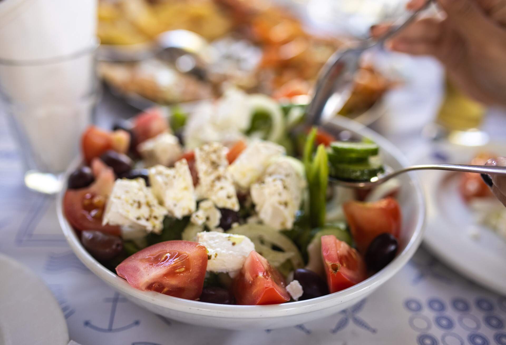 Woman eating Greek at restaurant, close-up, unrecognizable person