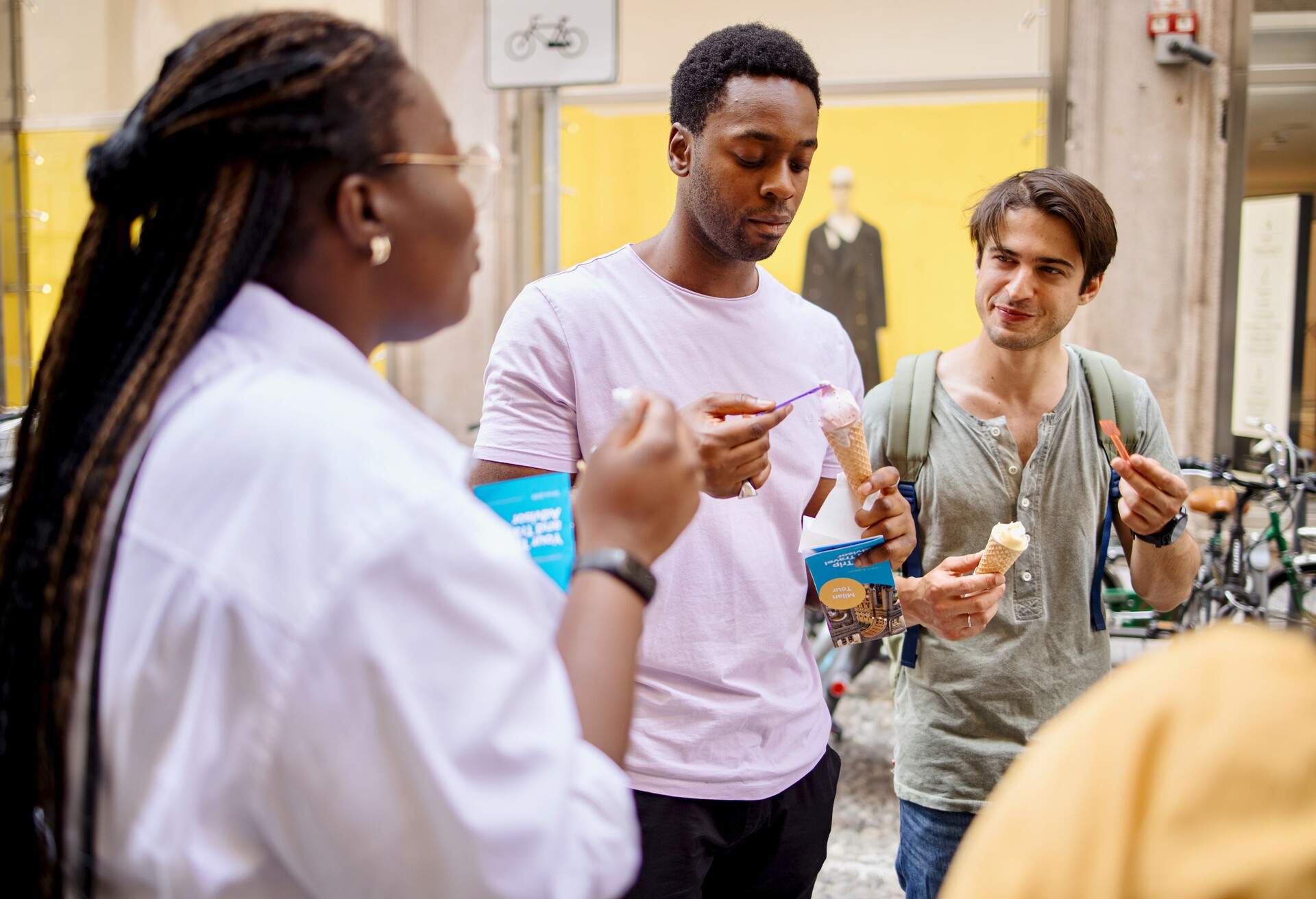 A group of multiracial people have a tour guide as they explore the city of Milan