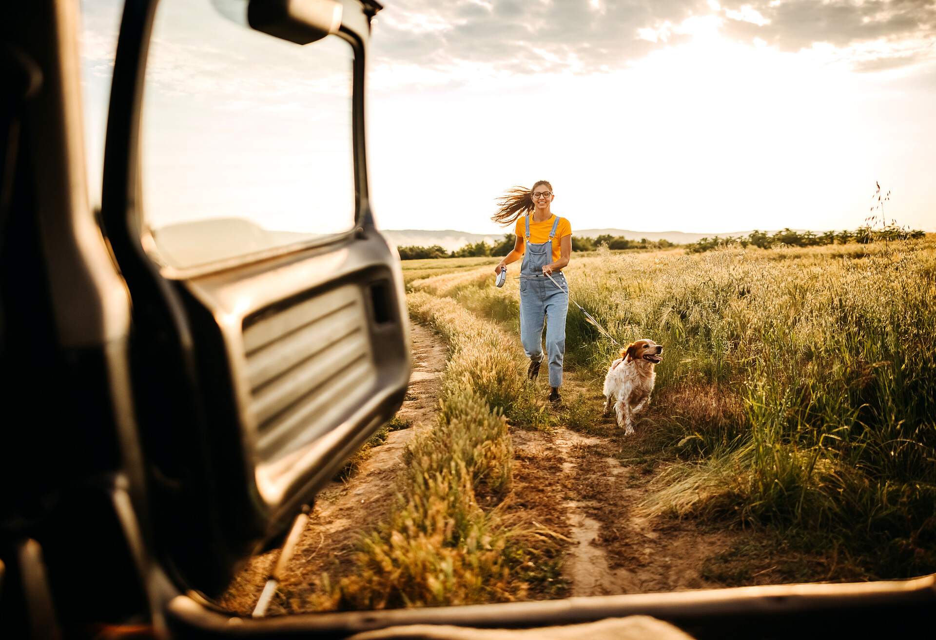 Woman runs with her dog through a field