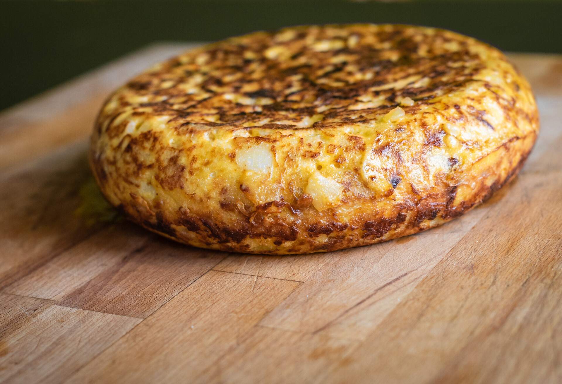 Spanish tortilla, Spanish omelette tortilla de patata. Typical traditional Spanish omelette dish or tapas with eggs, potato, onions andolive oil, served on wooden desk.