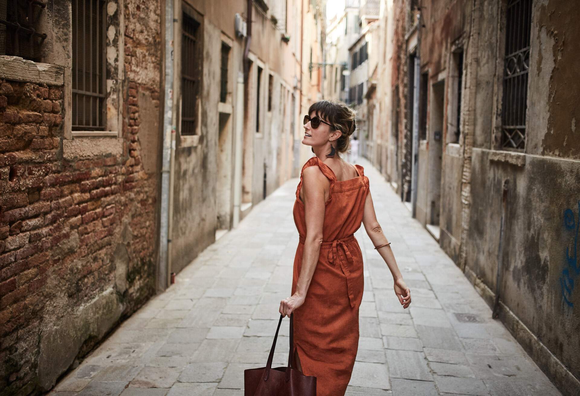 A young woman walks down an old street in Italy