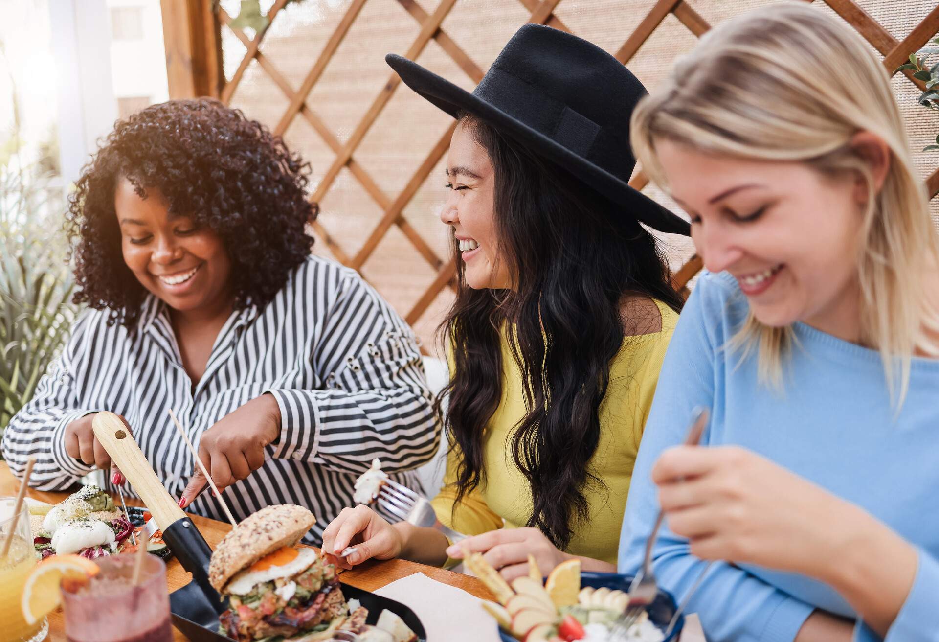 Young multiracial friends having breakfast outdoors in restaurant - Focus on asian girl face