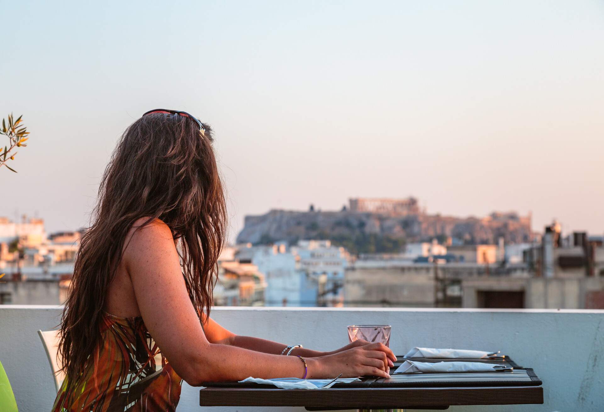 Woman at a restaurant enjoying the view of the Acropolis at sunset. Athens, Greece