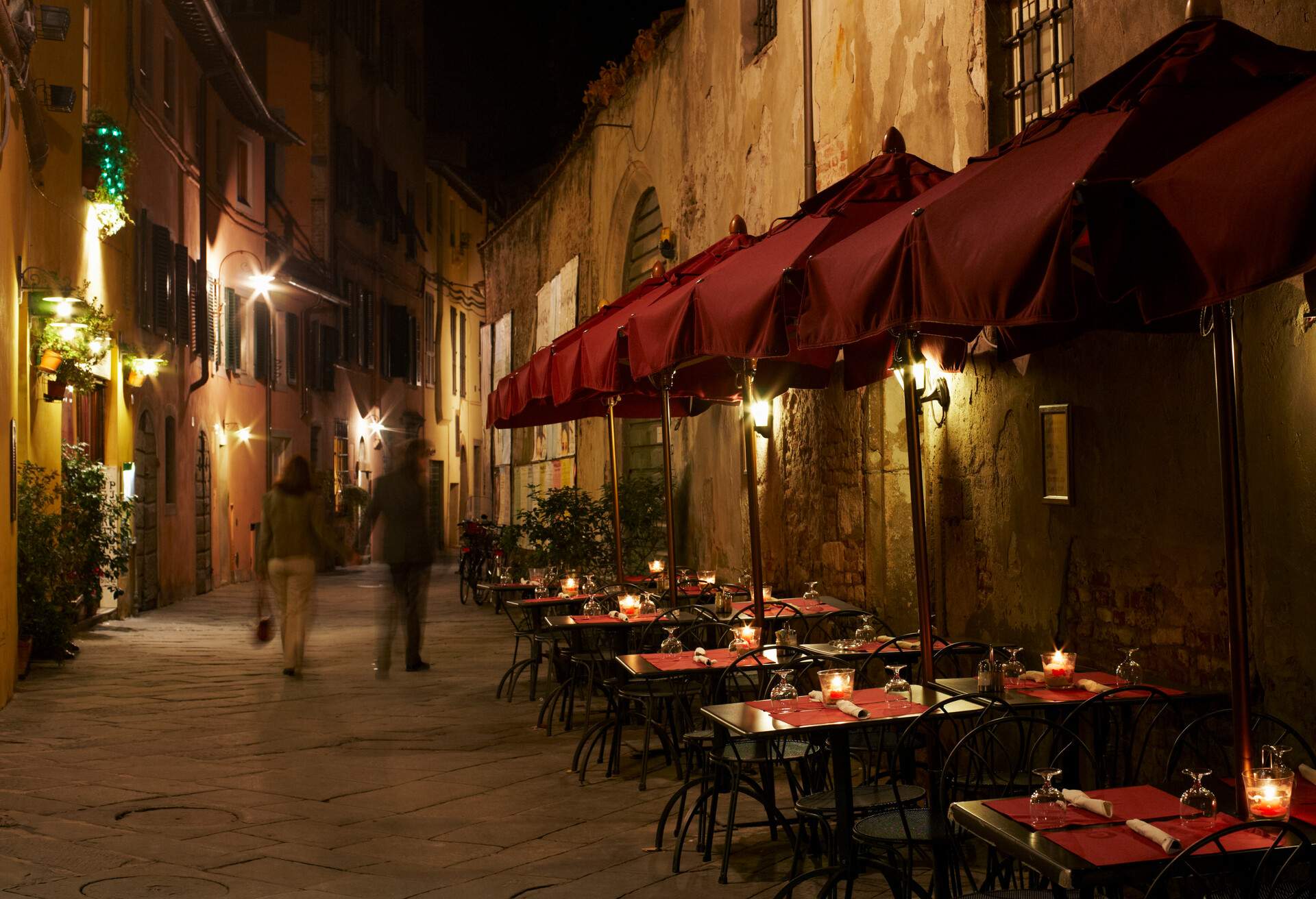 Italy,Emilia-Romagna,Bologna,Tourists walking along narrow street lined with Restuarants at night