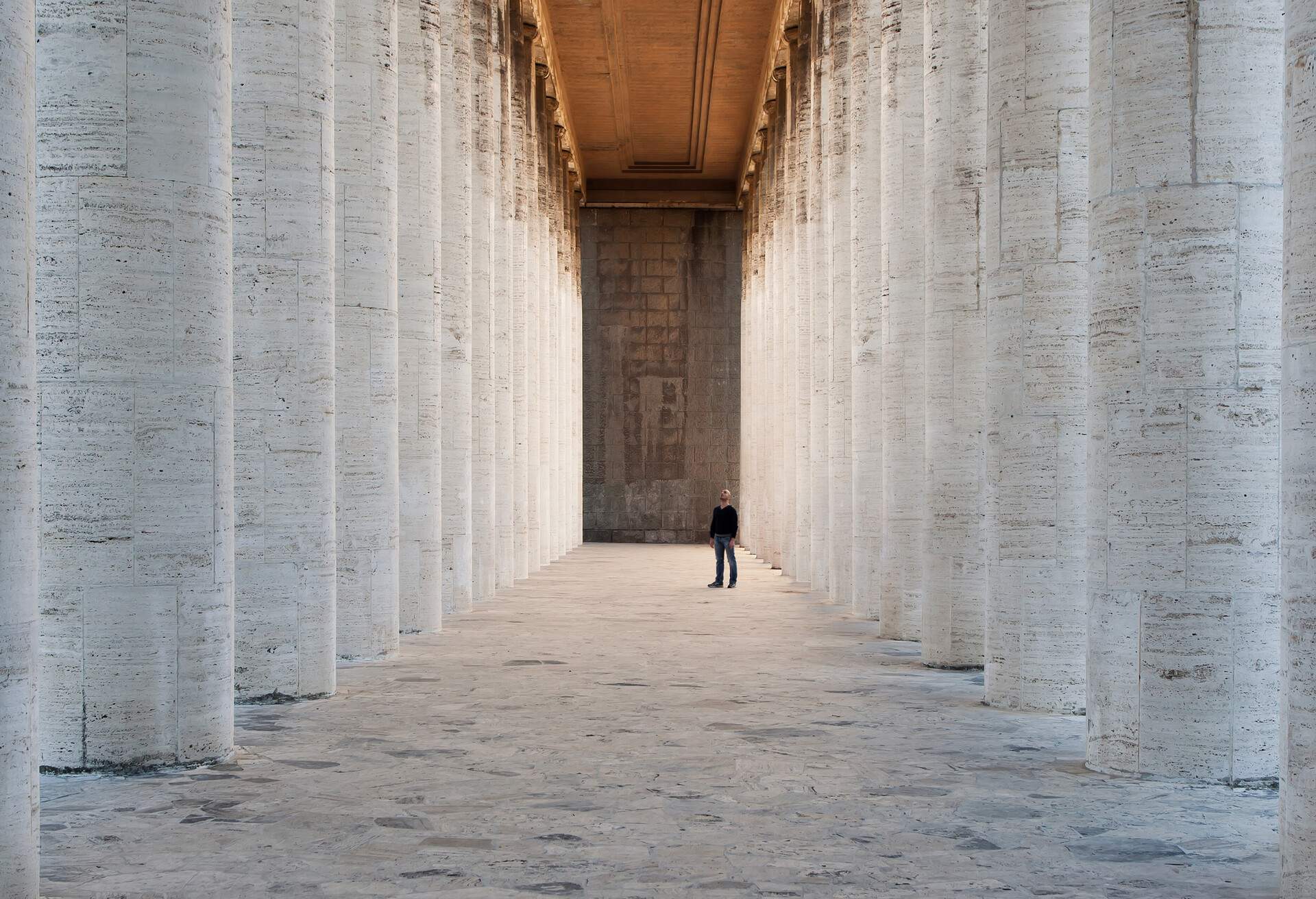 Astonished man standing under huge colonnade.