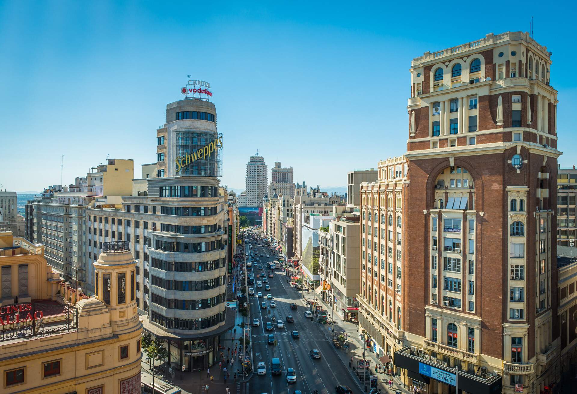 Crowds of shoppers, tourists and commuters bustling along the busy shopping street of Gran Via overlooked by the iconic billboards of this famous Madrid landmark, Spain.
