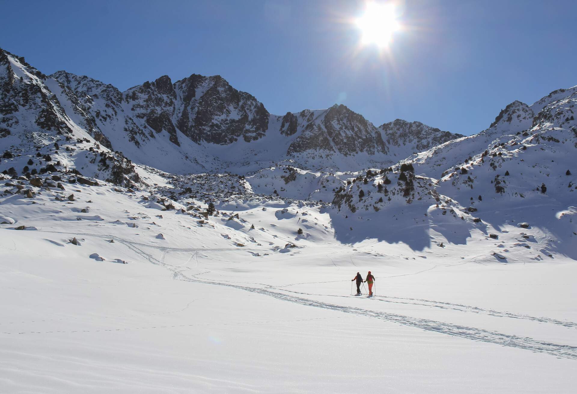 Two skiers inside beautiful snow capped mountains under a blue sky on a beautiful winter's day