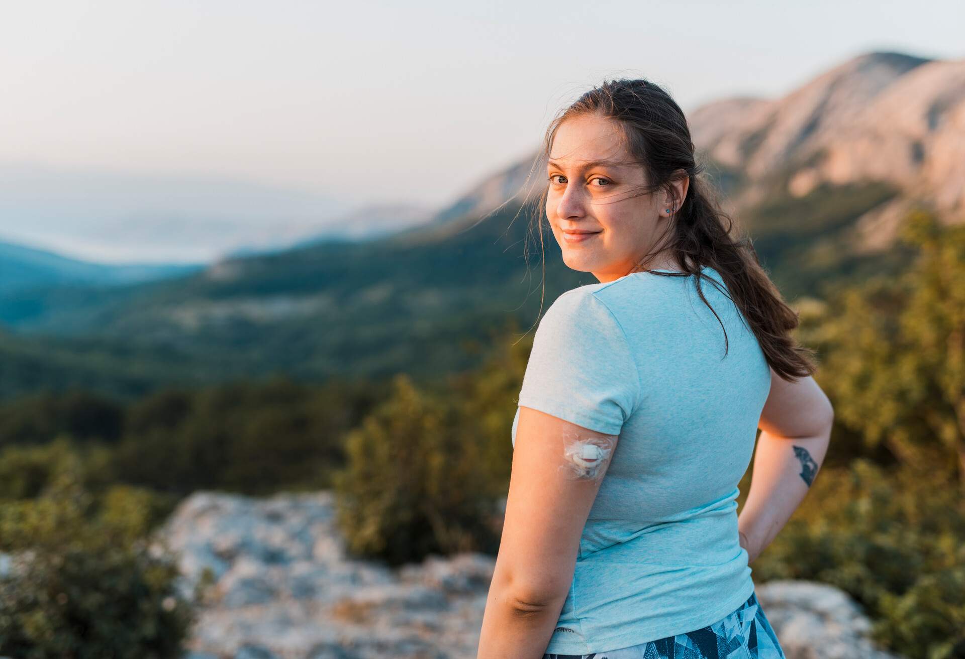 Woman with diabetes standing on top of the hill and looking at camera