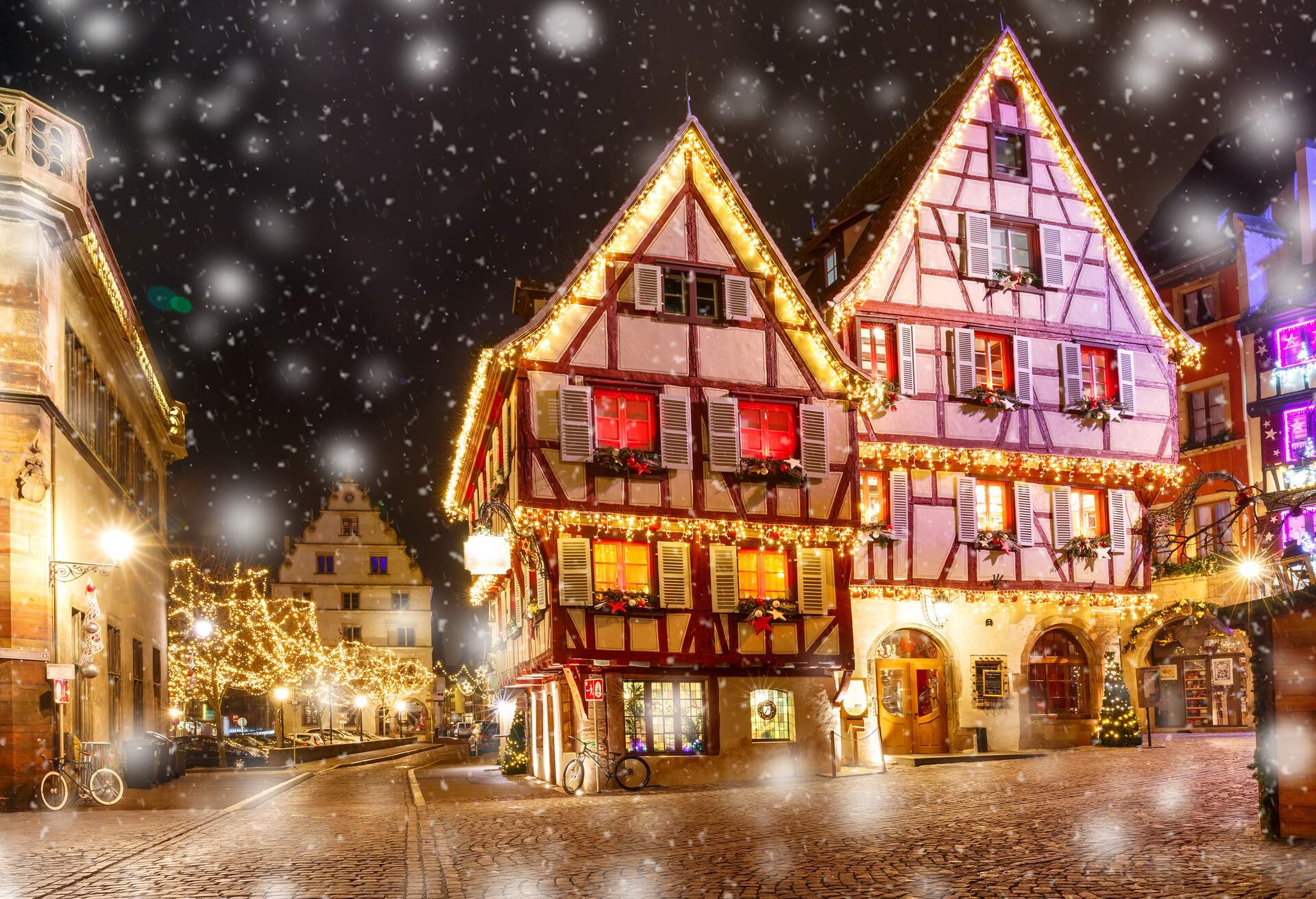 Traditional Alsatian half-timbered houses in old town of Colmar, decorated and illuminated at snowy christmas night, Alsace, France