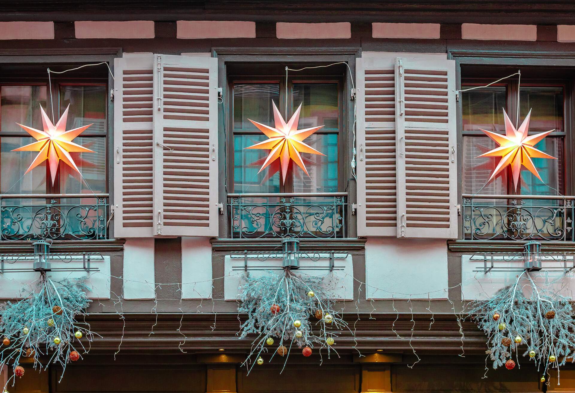 Christmas decorated half-timbered house with wooden shutters and railings in Ribeauville, Alsace, Eastern France.
