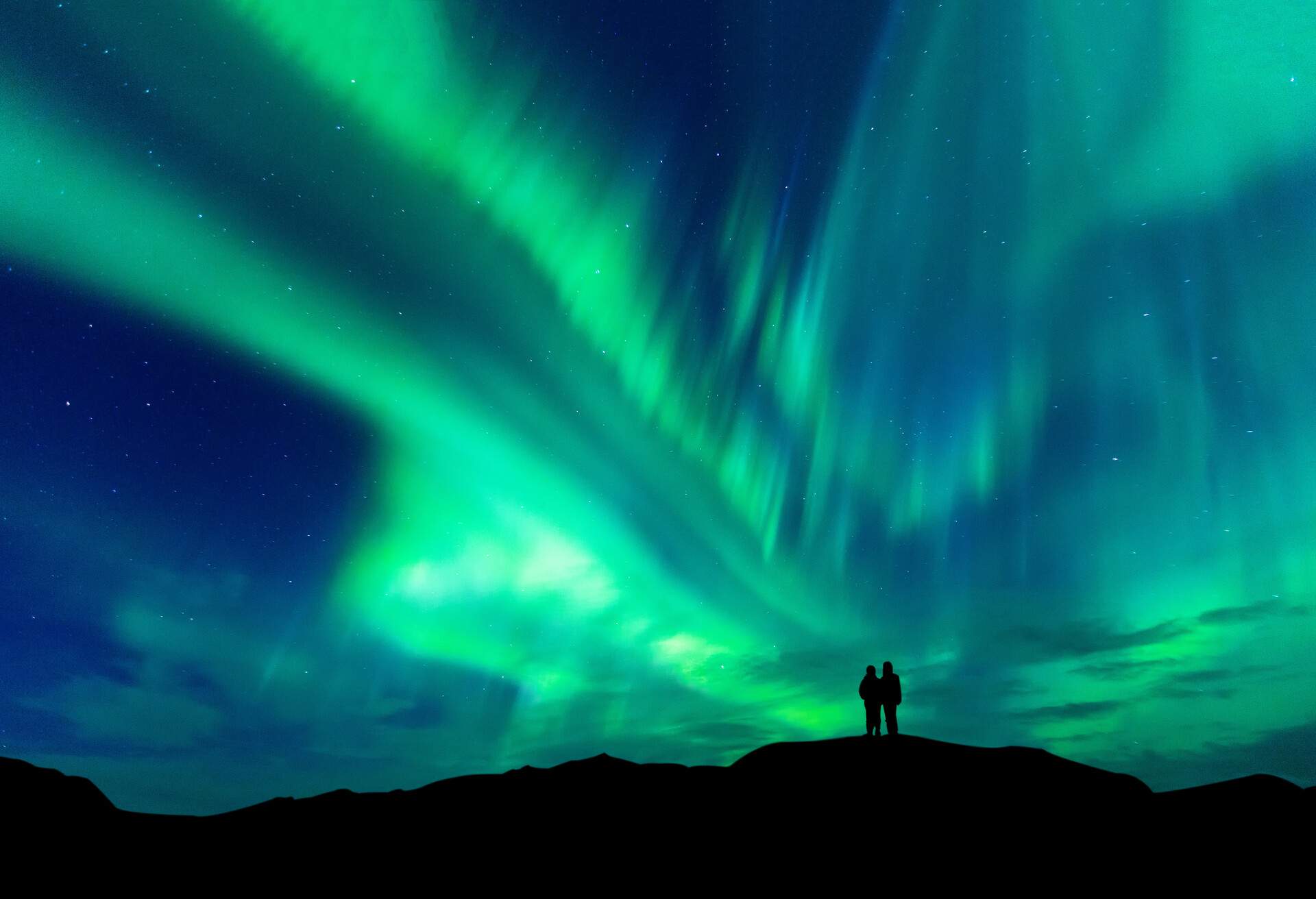 Aurora borealis with silhouette love romantic couple on the mountain.Honeymoon travel concept