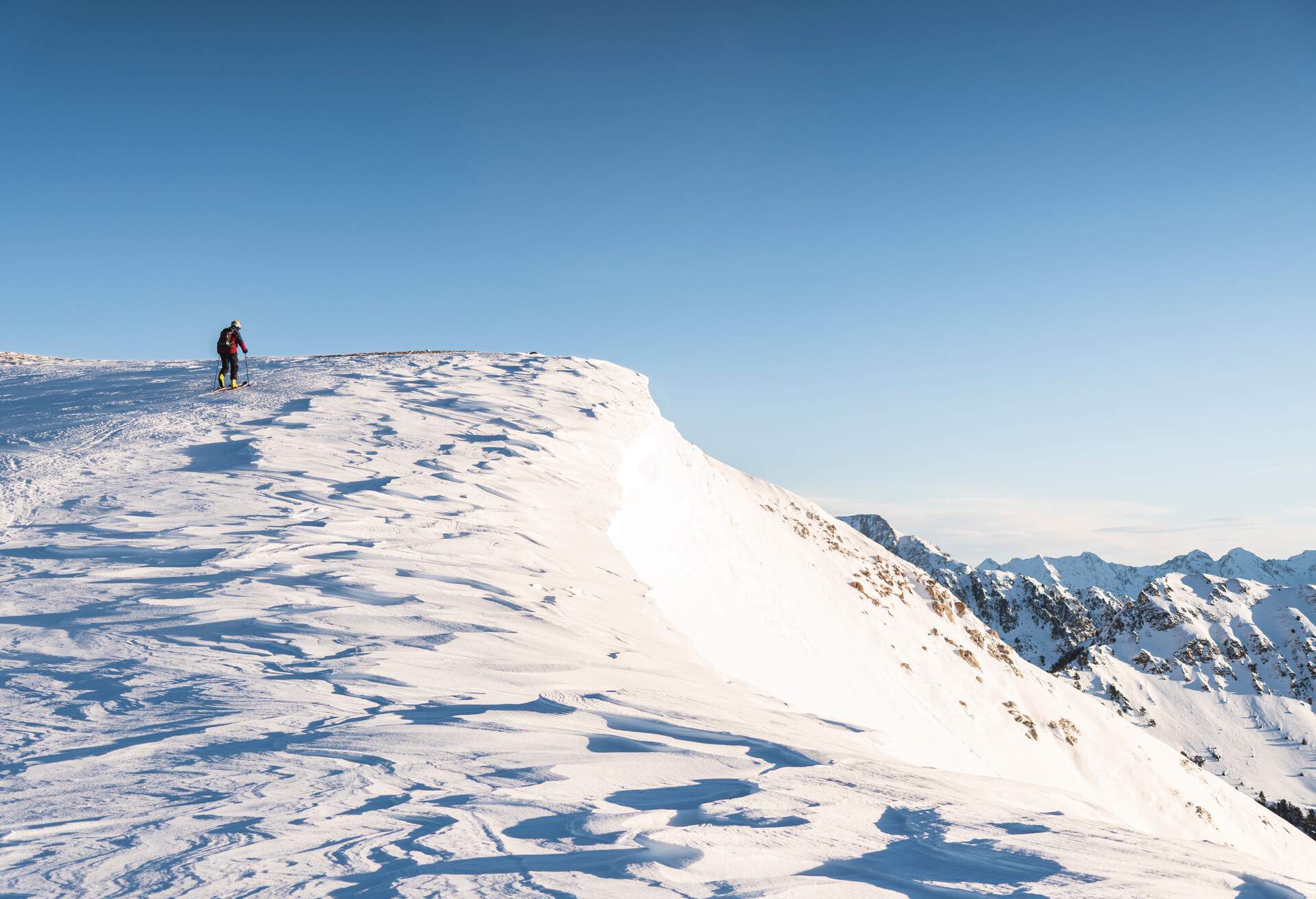 A man climbing up a snow-covered hill slope on skis.