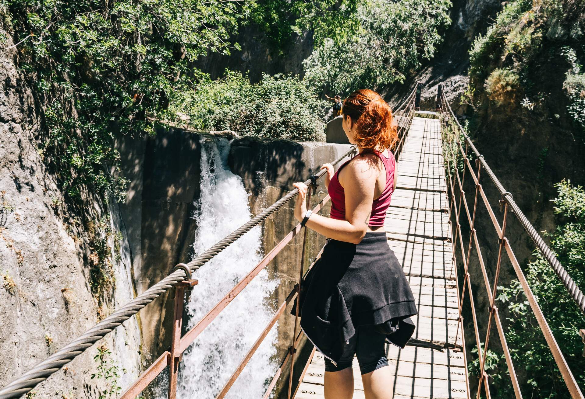 Young woman on a suspension bridge walking on the Los Cahorros route, Granada, Spain 