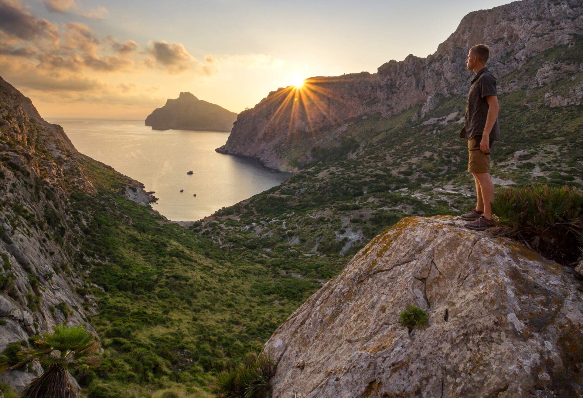 Incredible sunrise over Cap de Formentor and Cala Bóquer near Pollenca, Mallorca, Spain with a man on rock watching sunrise high above sea level; Shutterstock ID 1169584342; Brand (KAYAK, Momondo, Any): Any