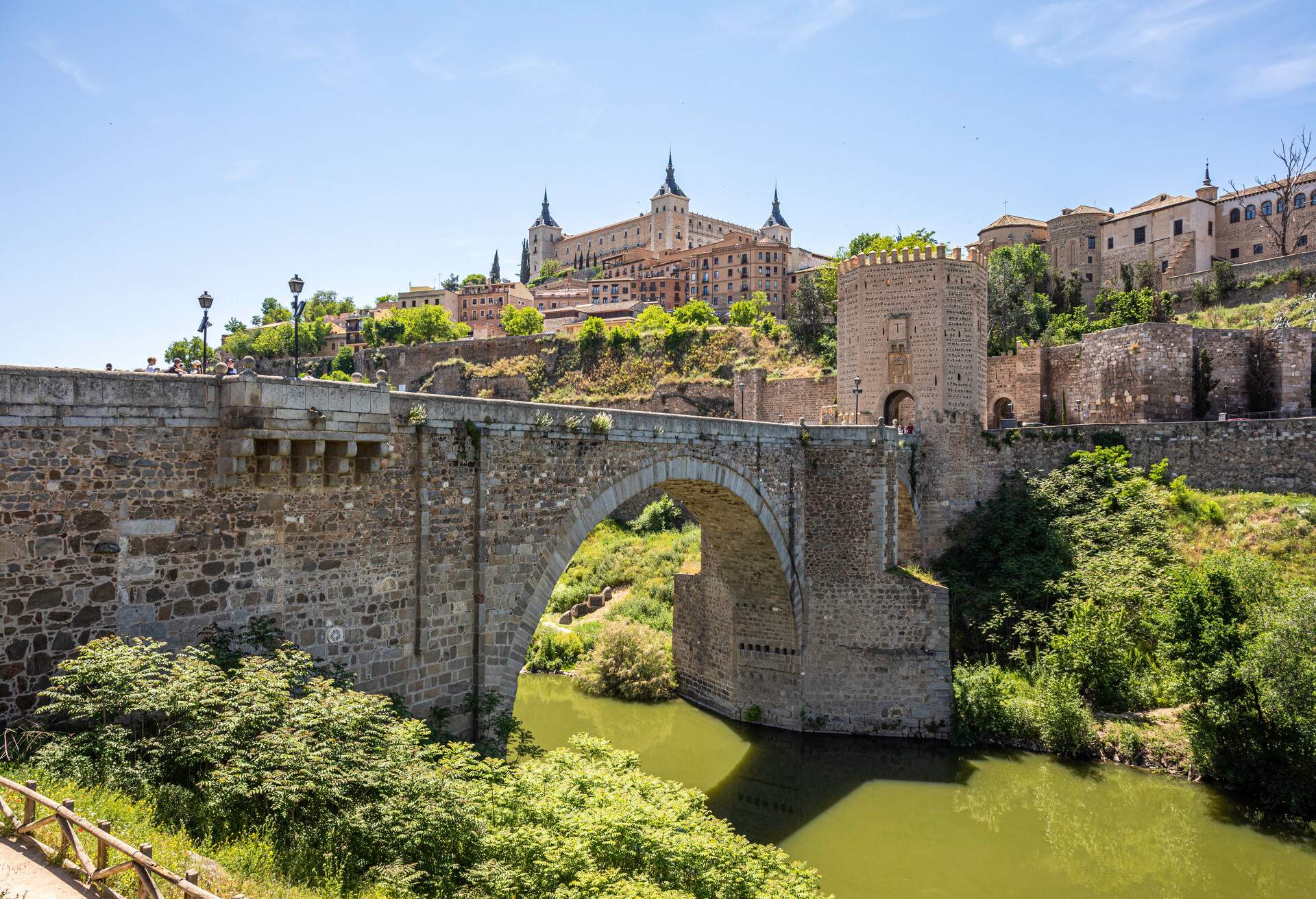 A view of Alcantara bridge over the river Tagus with the town Toledo on the other side of the bridge. The stone arch bridge was built over the Tagus River between 104 and 106 AD by an order of the Roman emperor Trajan.