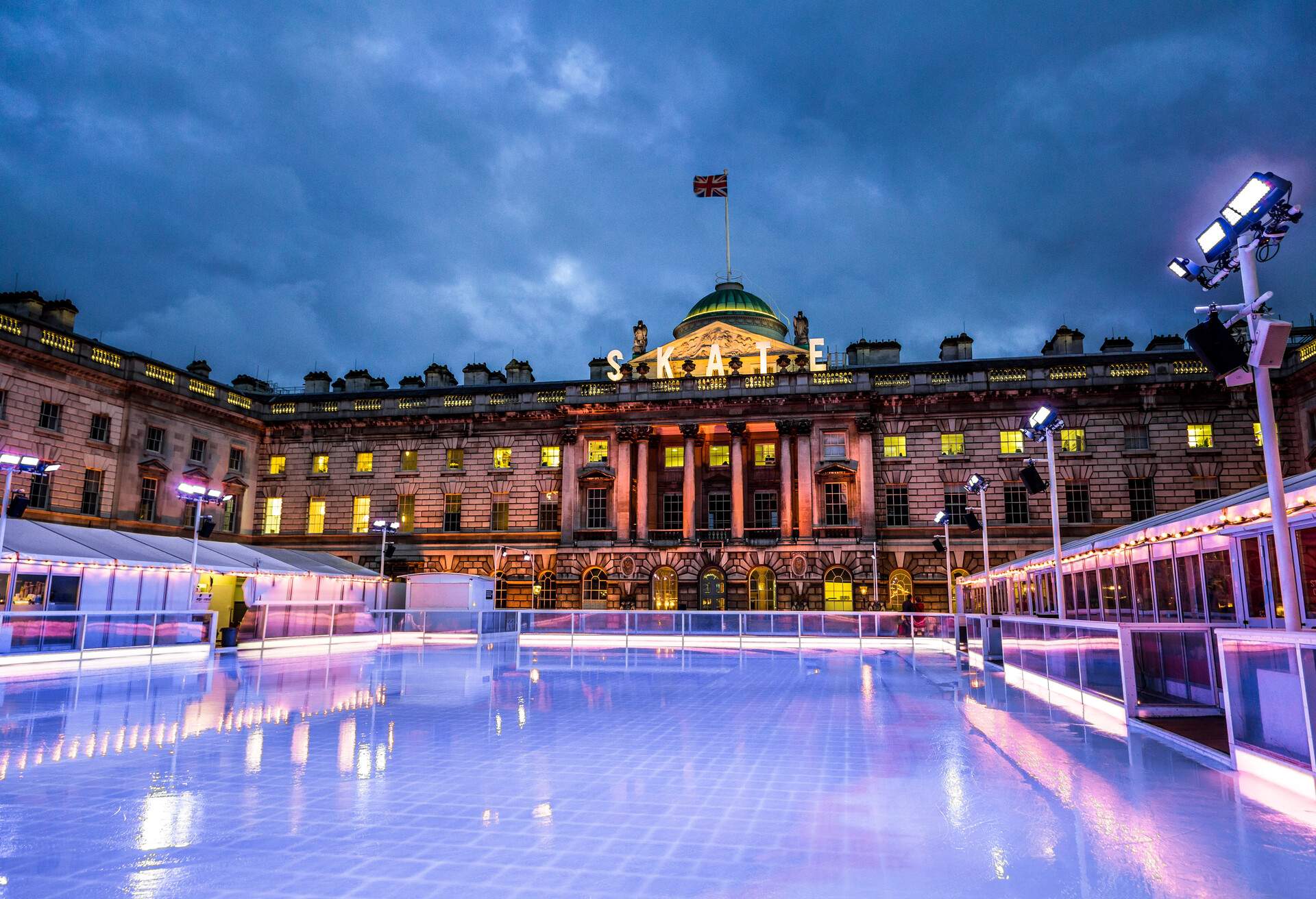 The Christmas ice skating rink at Somerset House on The Strand in central London, UK. The ice rink is empty with no people on it, as it is just about to be cleaned and maintained by the special ice machines. The sun is about to set and the sky features a moody and ominous cloudscape. Horizontal colour image with room for copy space.