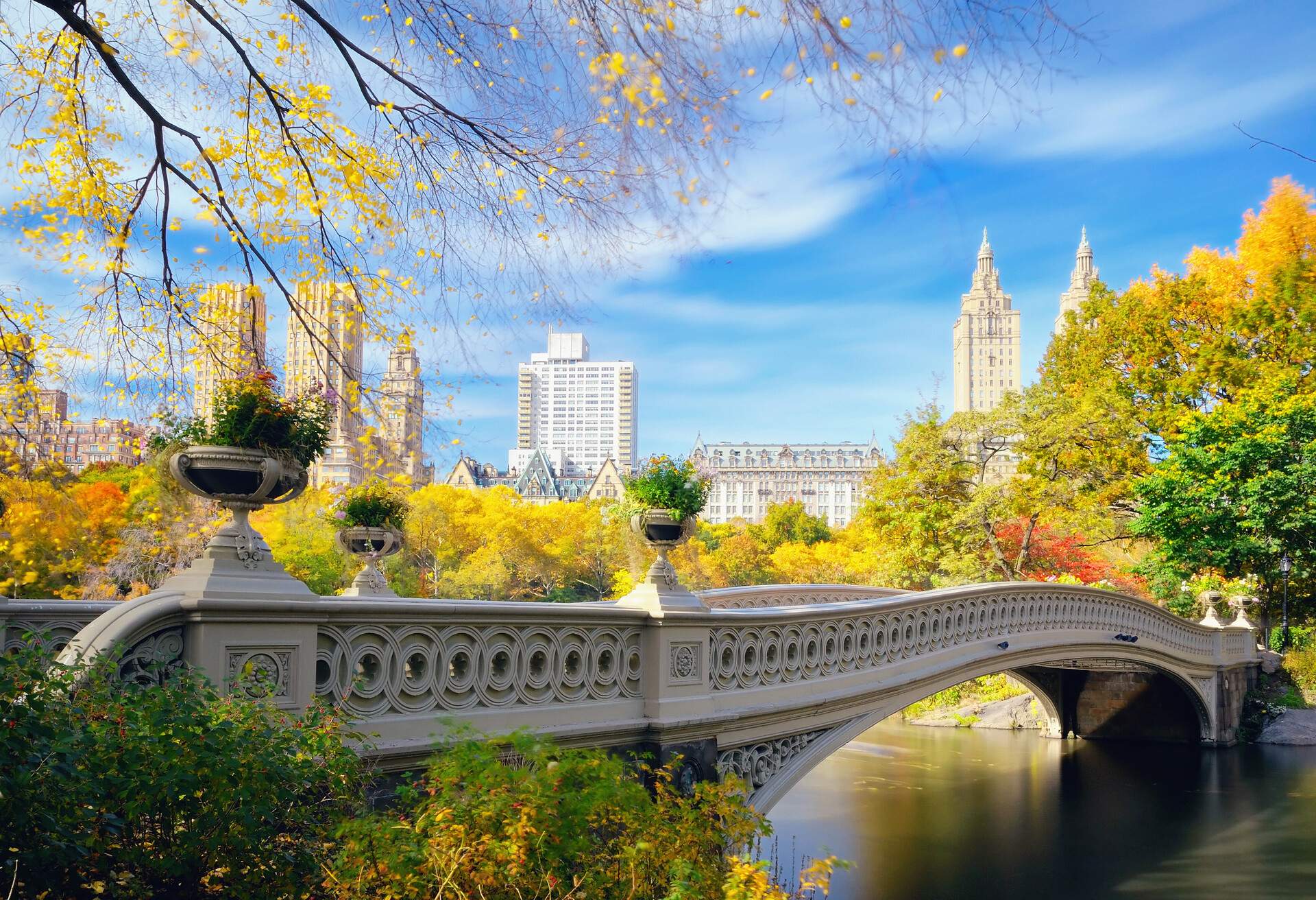 Long exposure of Bow Bridge in Central Park, New York City, in autumn with buildings of Central Park West in background.