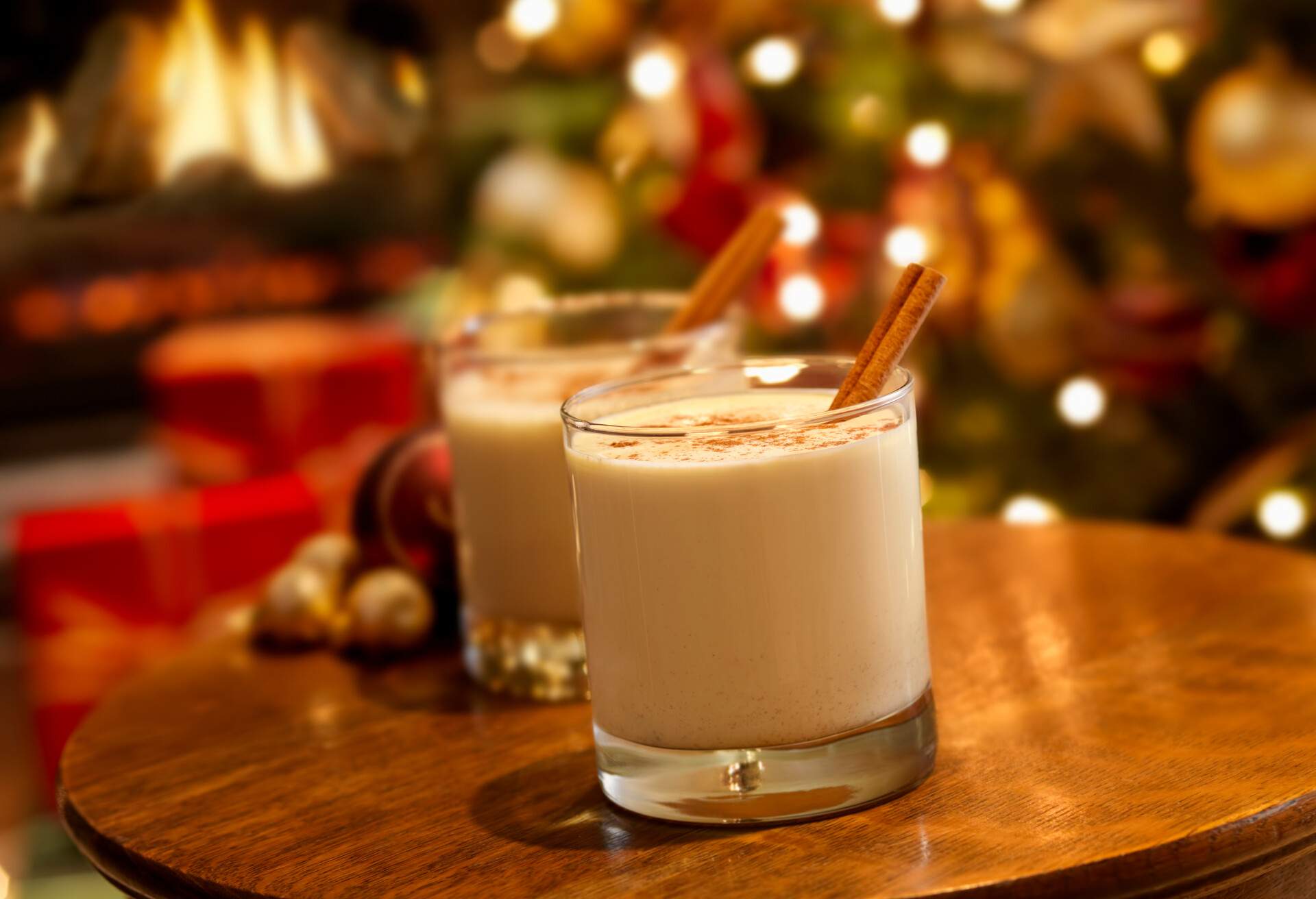 Two egg milk punch topped with cinnamon powder and stick on a wooden table.