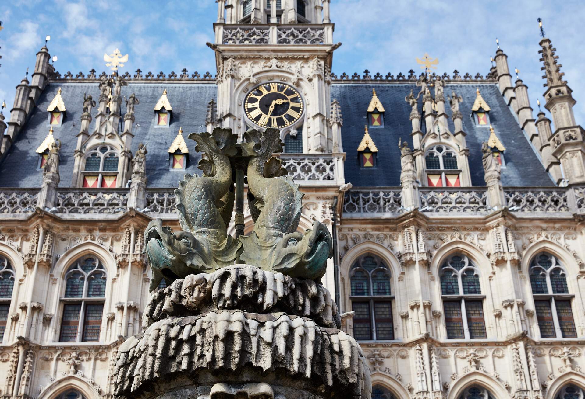 Oudenaarde, Belgium - September 13, 2022. Oudenaarde Town Hall and Belfry. The Town Hall was built in 1526-1537 and is inscribed on the UNESCO World Heritage List. The exterior architecture is secular Brabantine Gothic. Royal fountain in foreground.