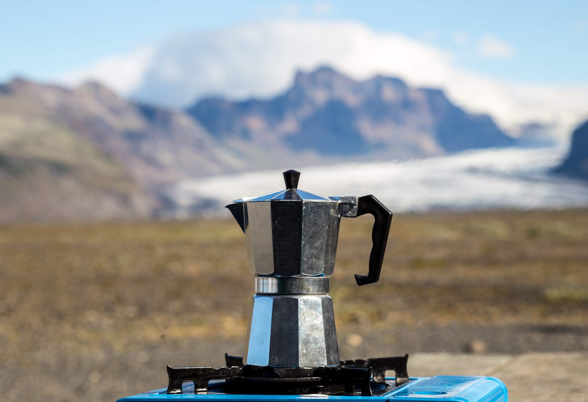 Moka pot on a gas stove at a picnic area, mountains in the background