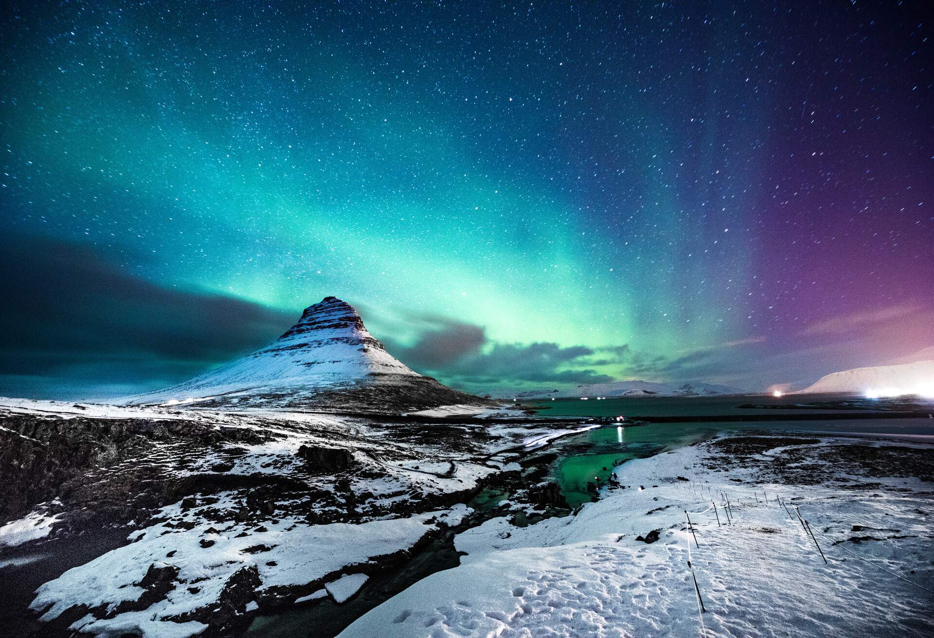 Solo traveler walking in front of an awesome Northern Lights in Mount Kirkjufell Iceland. 