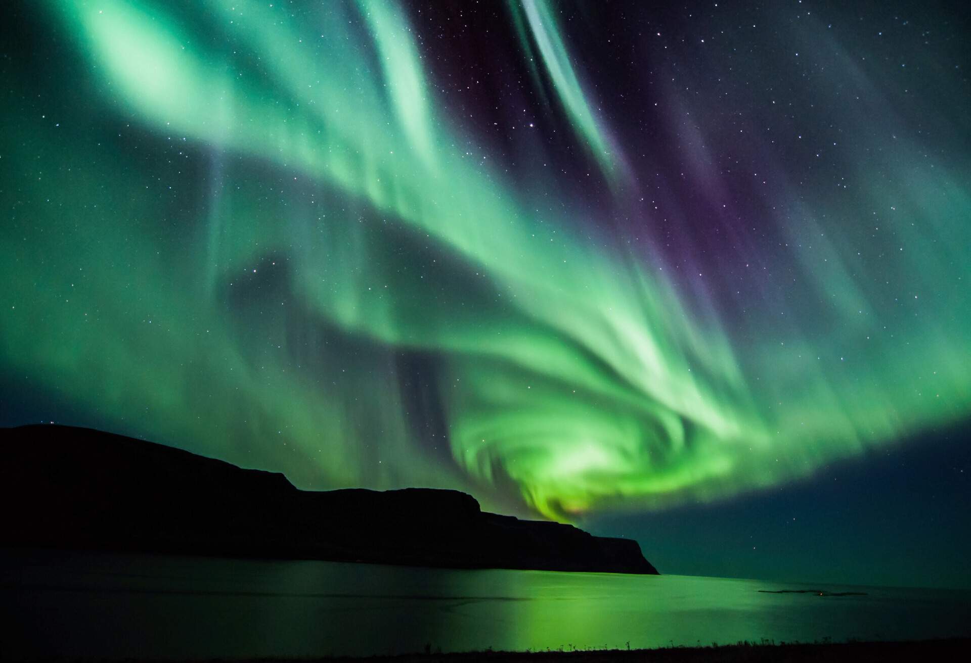 Swirls of green and blue lights of Aurora Borealis on a starry night.