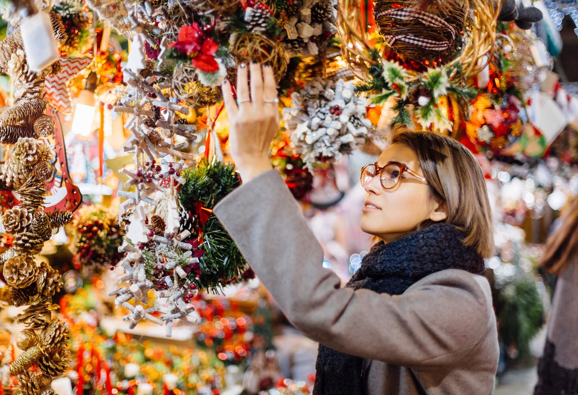 A woman with glasses looking at an ornament on display in a store.