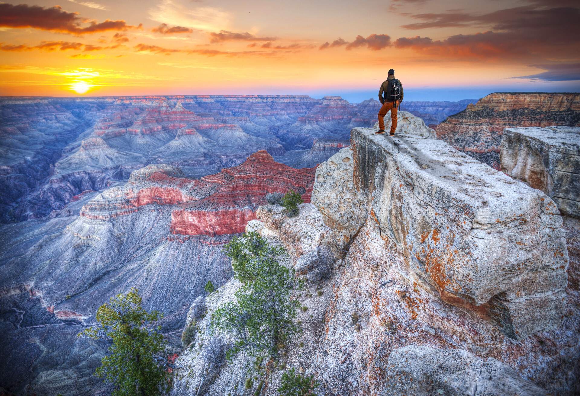 A man stands on top of a rocky mountain overlooking the Grand Canyon landscape, Arizone, USA.