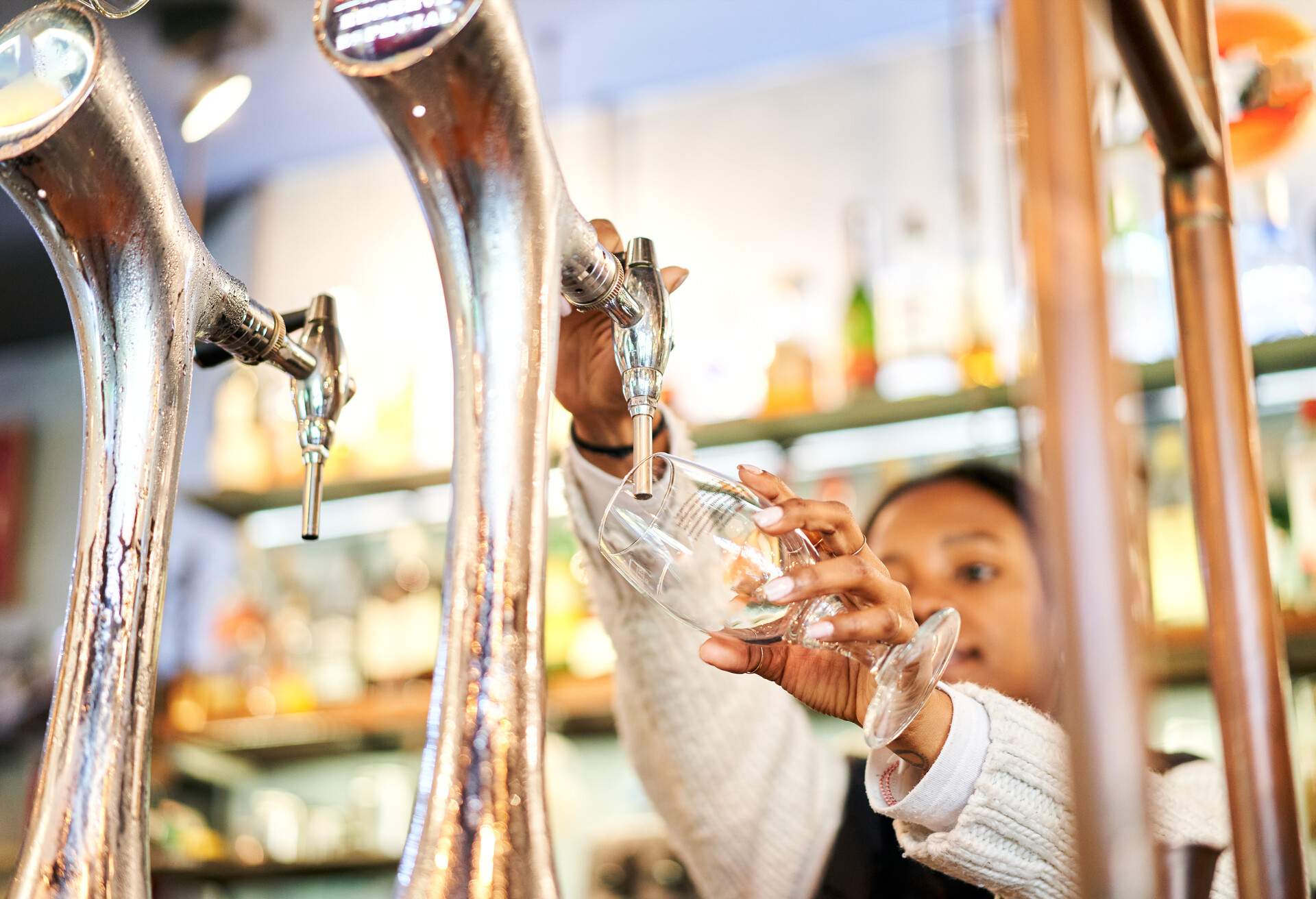 Close-up of a African American bartender  woman pouring a glass of tap beer in a bar.