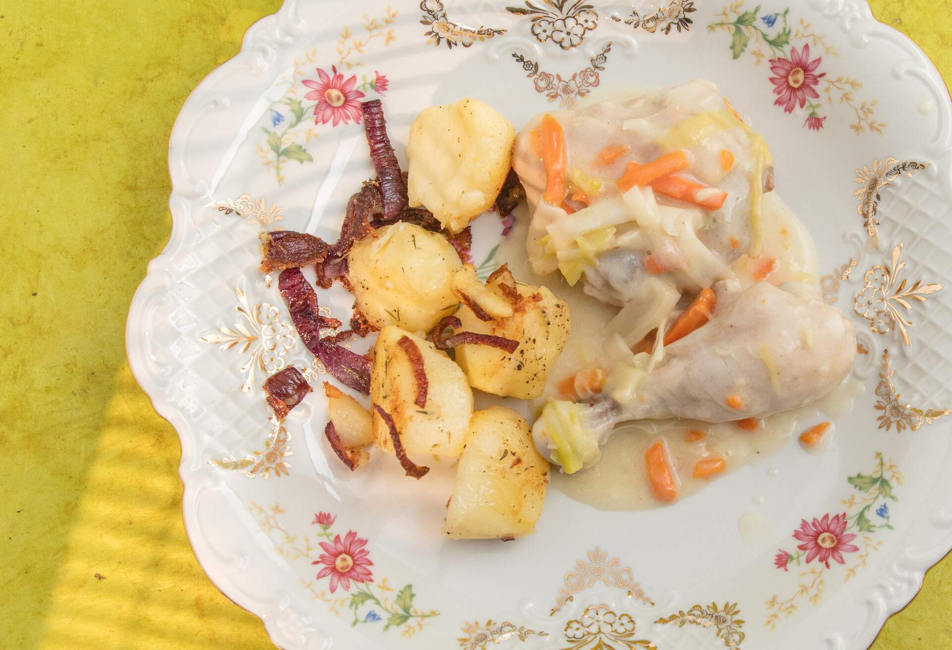 Gentse waterzooi with chicken and browned potatoes with red onion. Decorative plate. High point of view. Yellowish surface. High point of view.