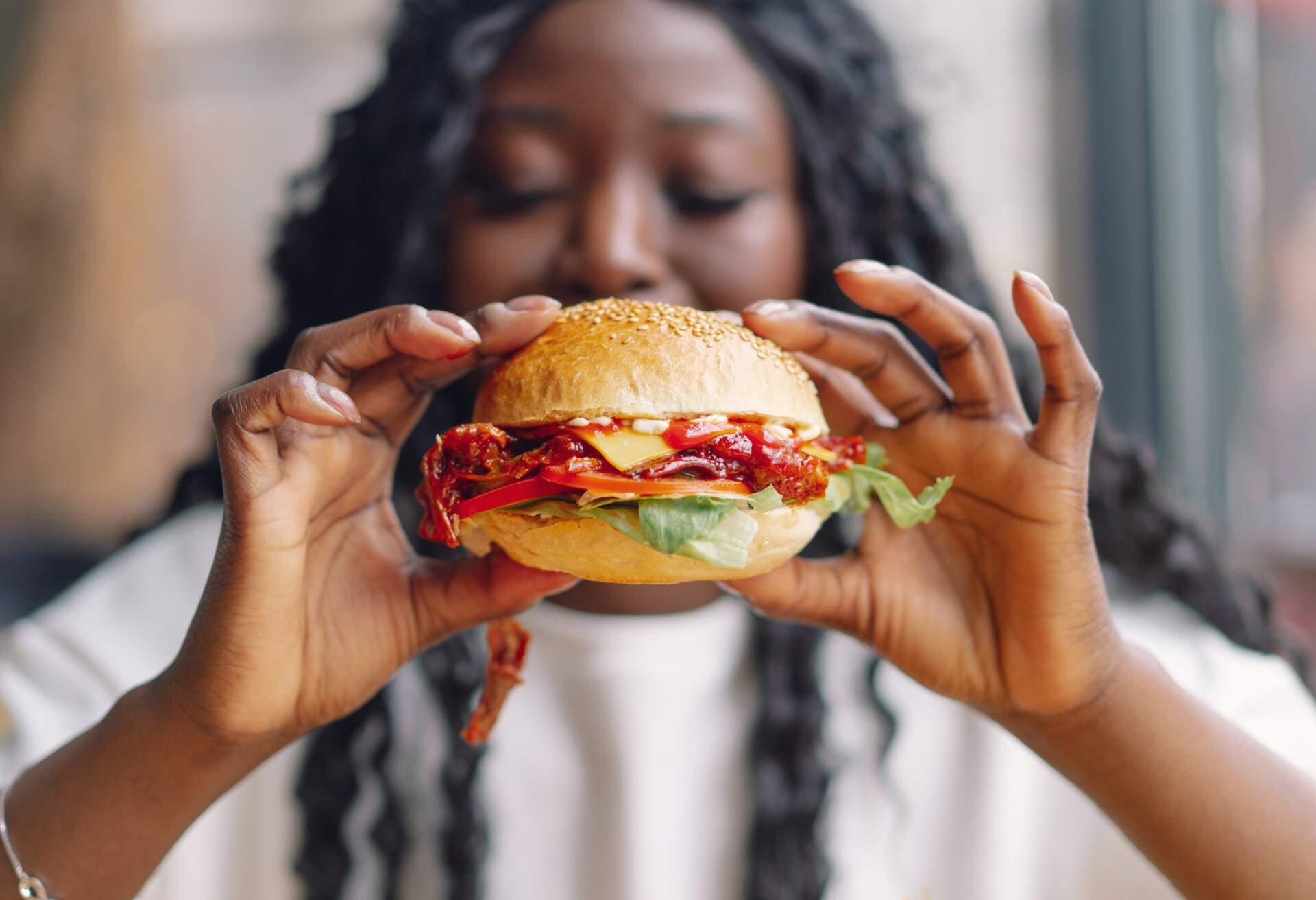 African woman with afro hair eating a tasty classic burger with fries. Cheat Meal.