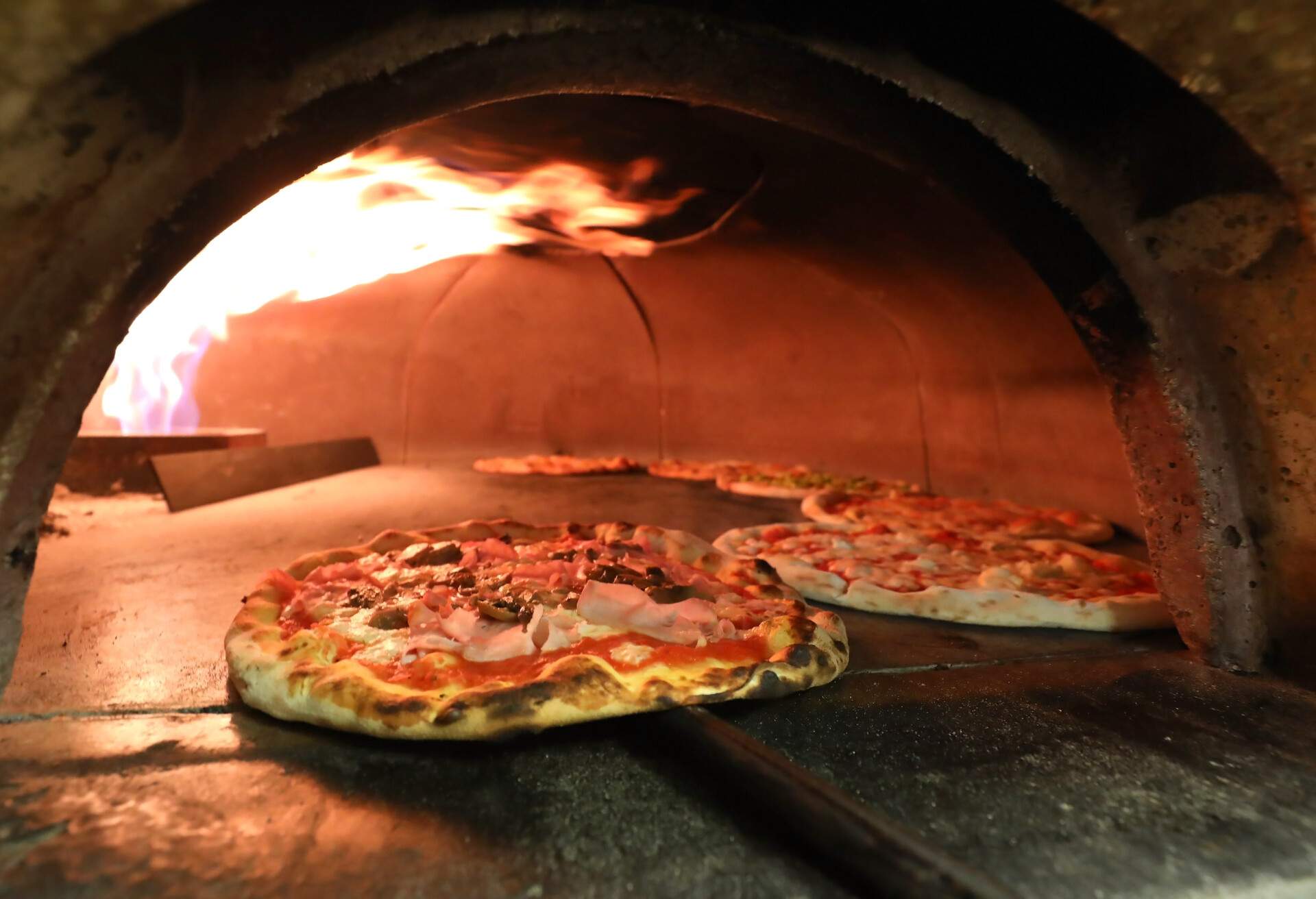 fire and many pizzas inside an oven in the italian pizzeria