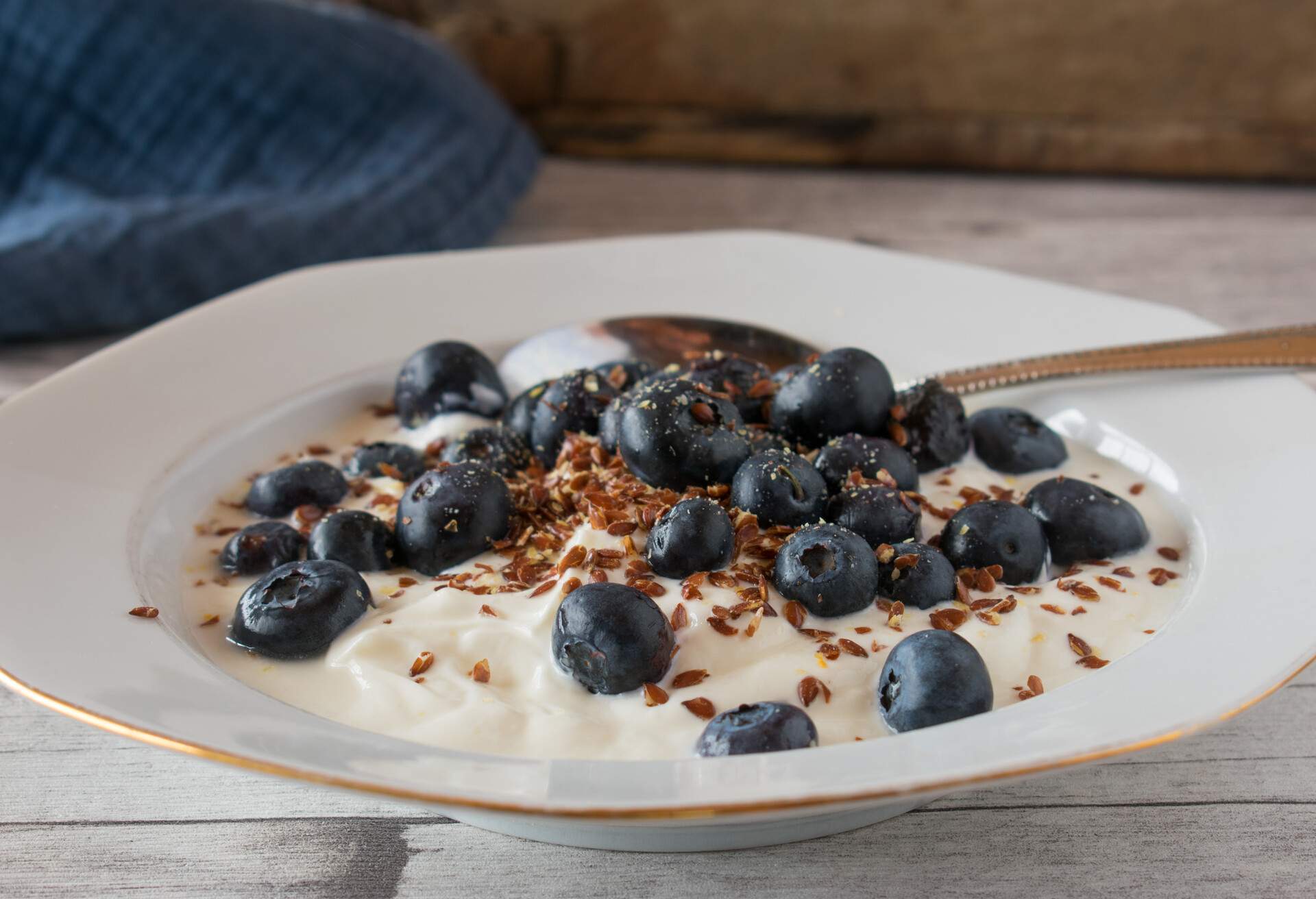 fresh and homemade high protein and low carb meal with skyr, fresh blueberries and linseeds served on a white and rustic plate with wooden table background. Front view
