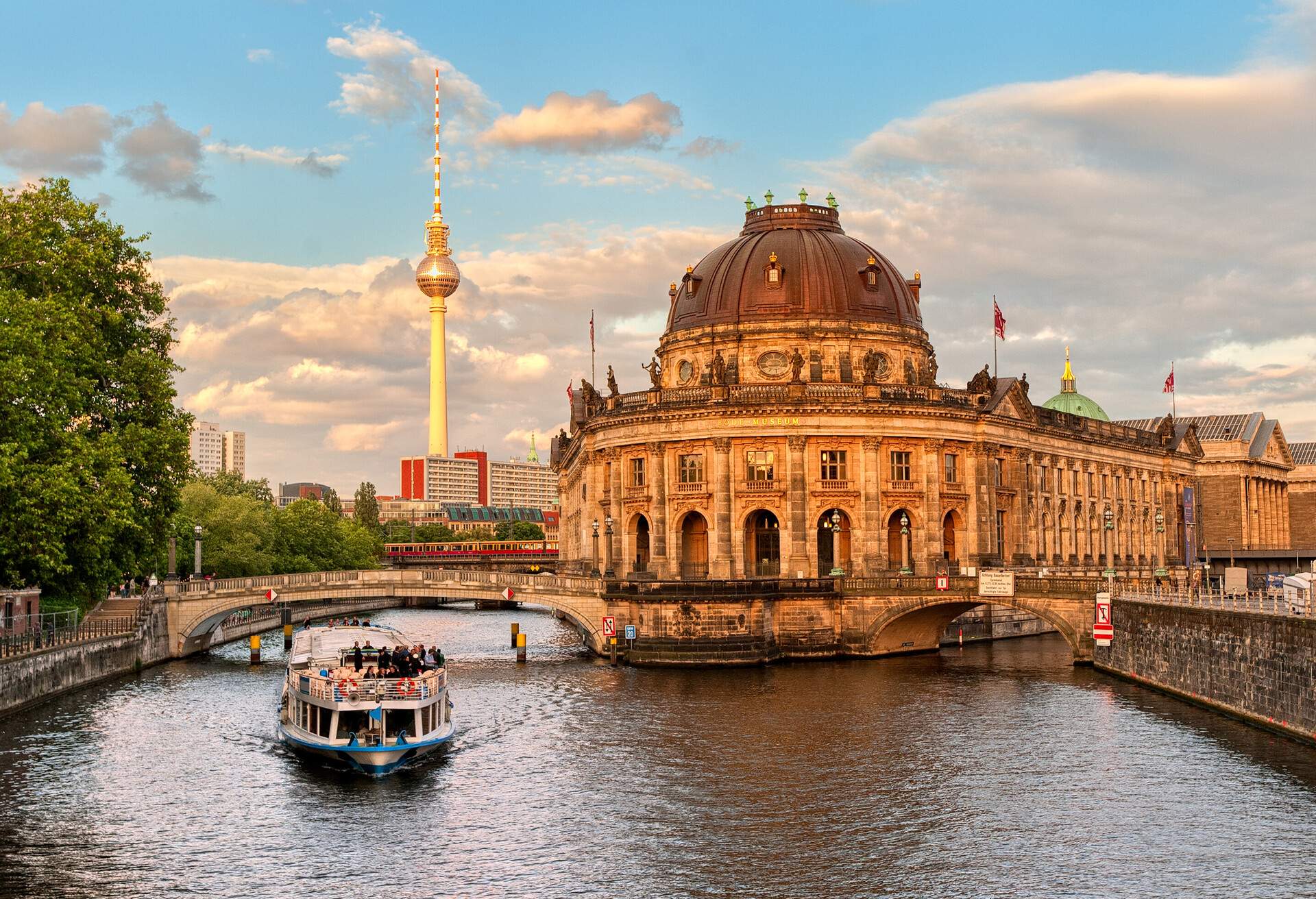 A Museum island on Spree river and Alexanderplatz TV tower in center of Berlin, German boat cruises a river with views of the Baroque-style Bode Museum and the Berlin TV Tower.