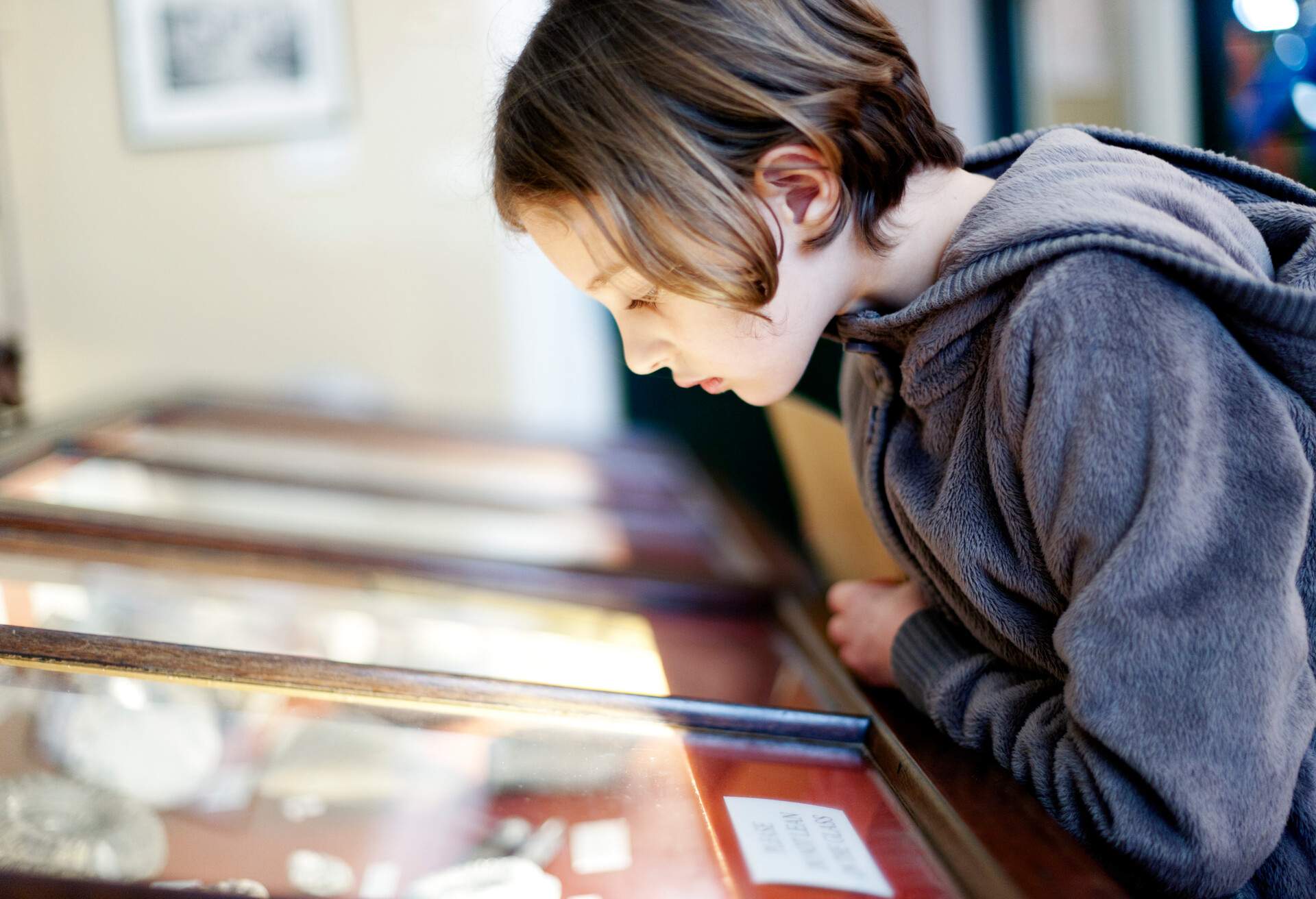 A young female child looking at a tabletop glass display.