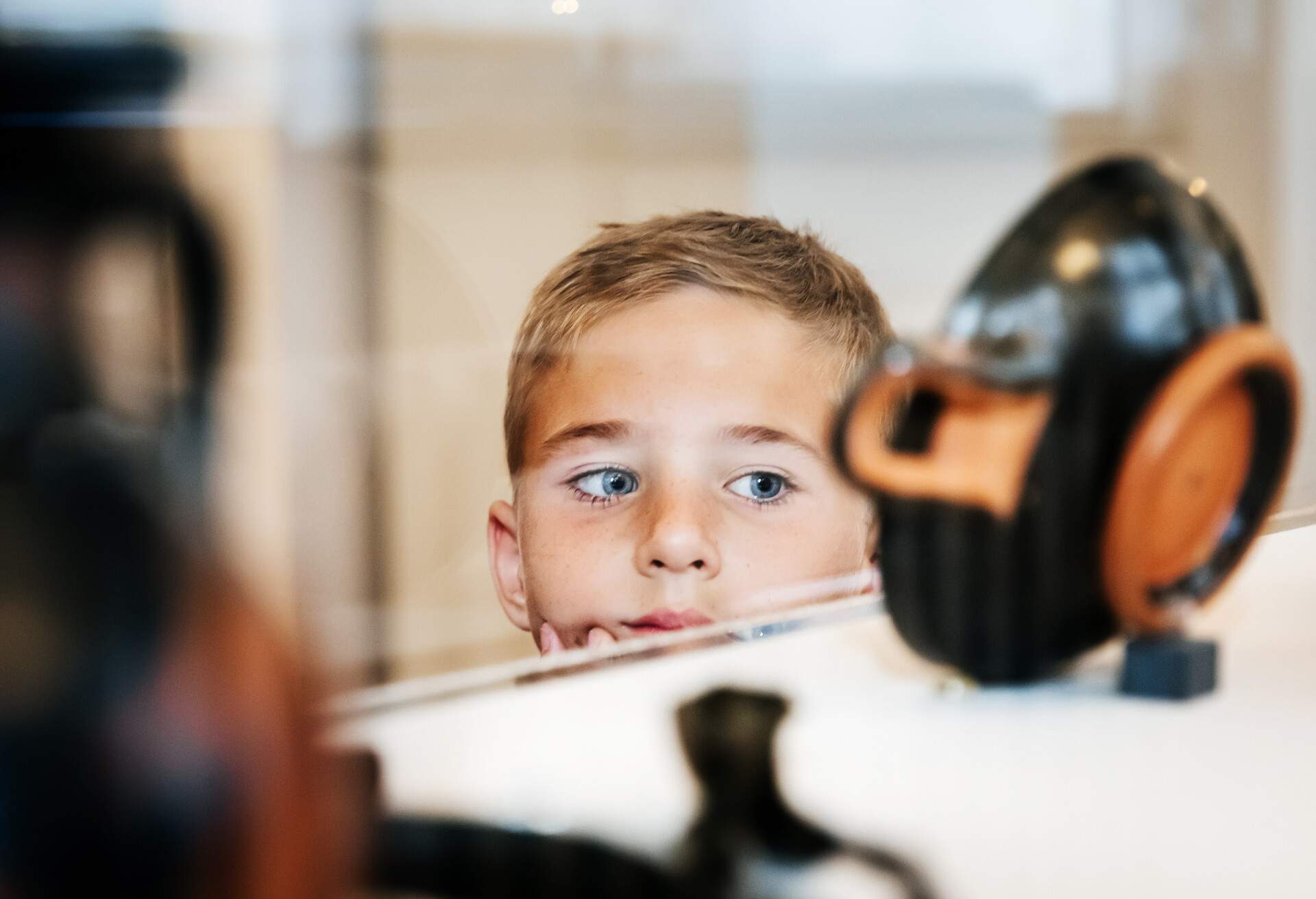 A young boy looking at some ancient artifacts on display in a museum while on a field trip with his classmates.