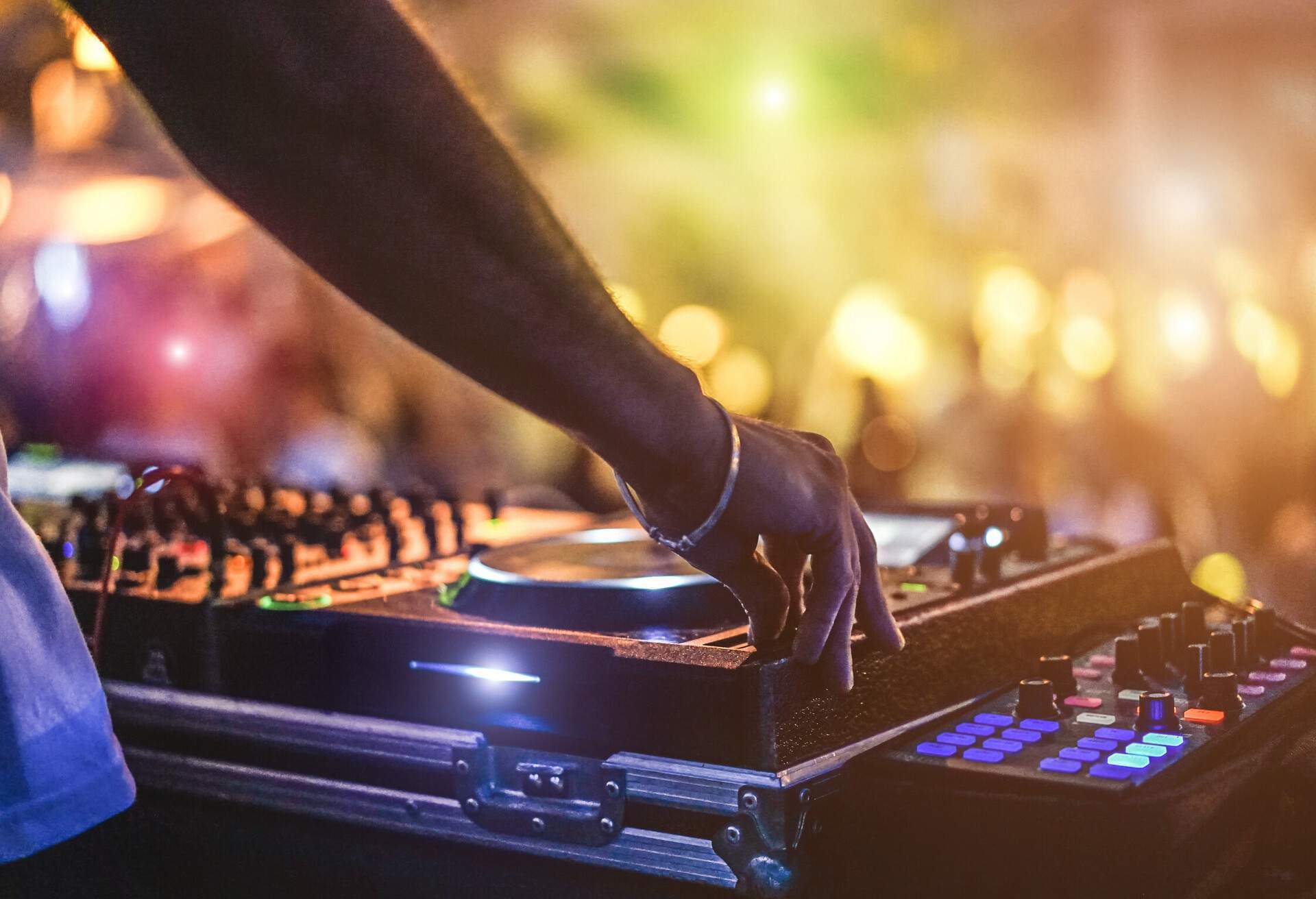 Dj mixing outdoor at beach party festival with crowd of people in background