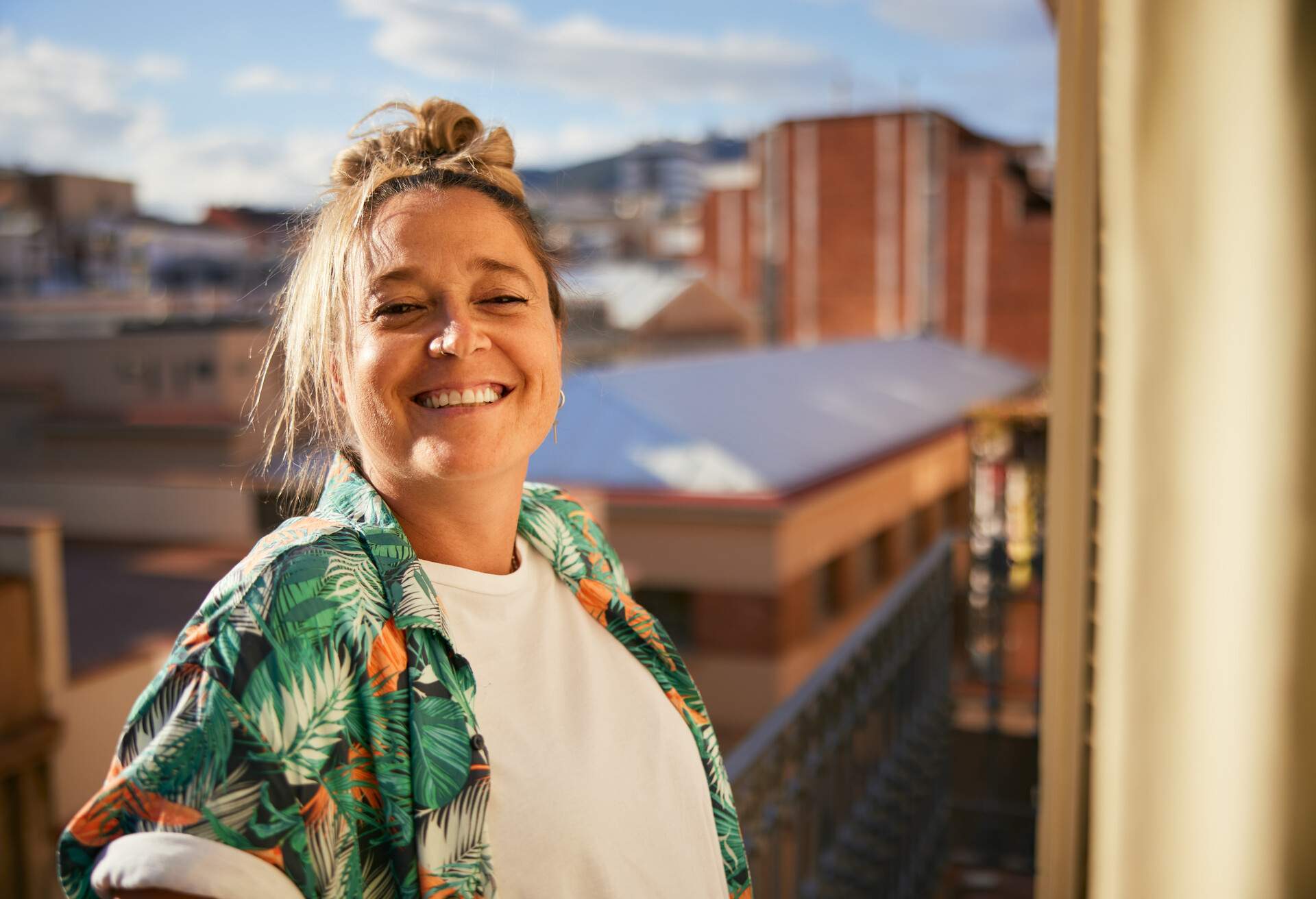 Headshot portrait of a woman smiling at the camera on a balcony. 